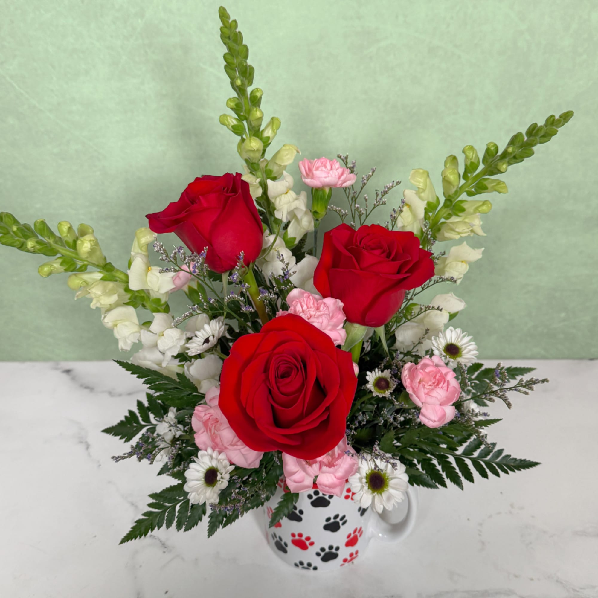Red roses and pink carnations in a paw-print mug vase