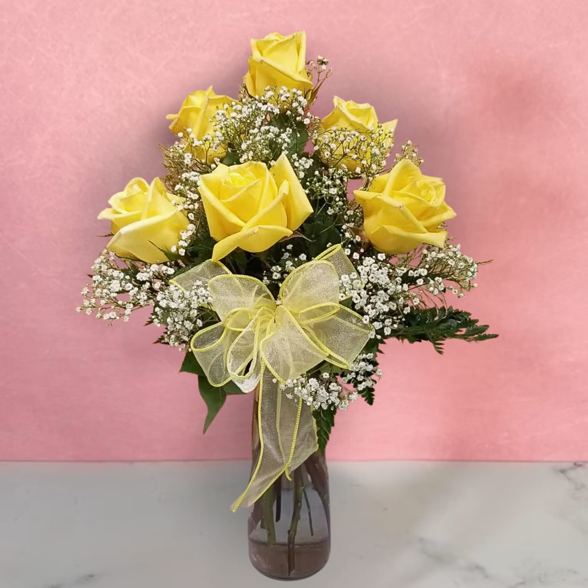 Yellow roses in a glass vase with a yellow ribbon bow