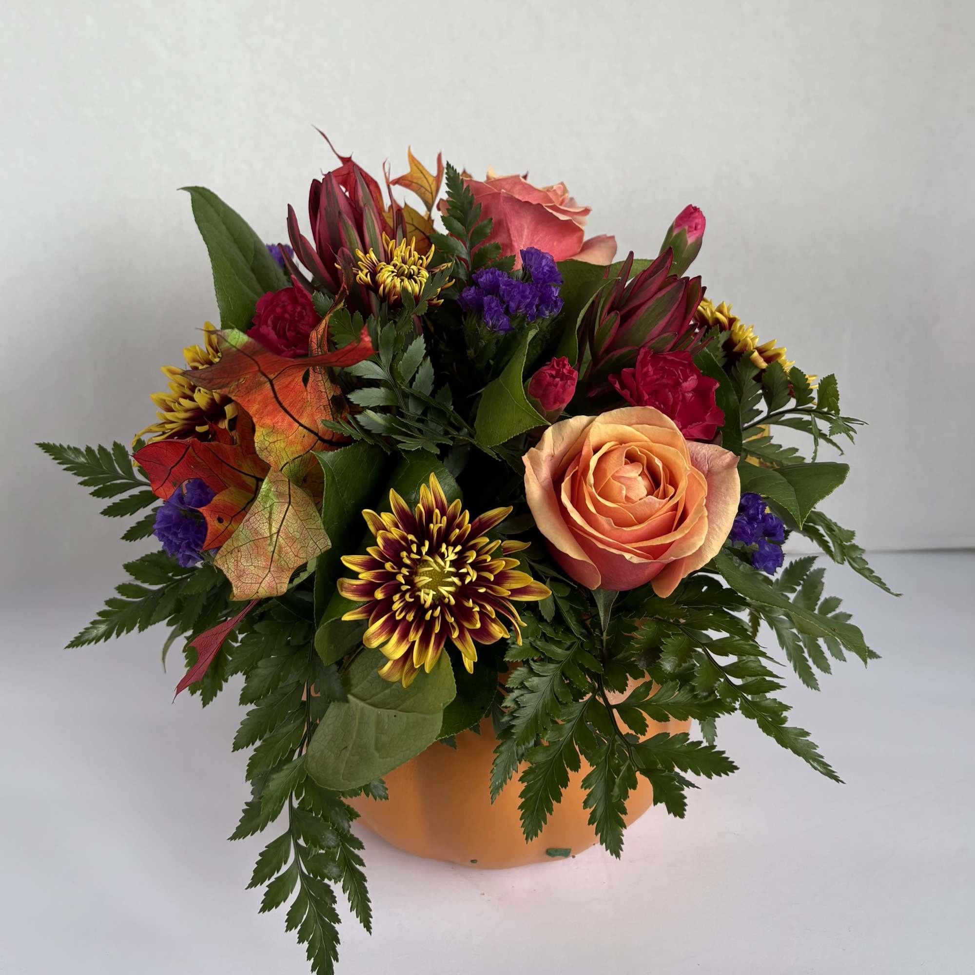 Mixed bouquet of roses and chrysanthemums in an orange pumpkin container