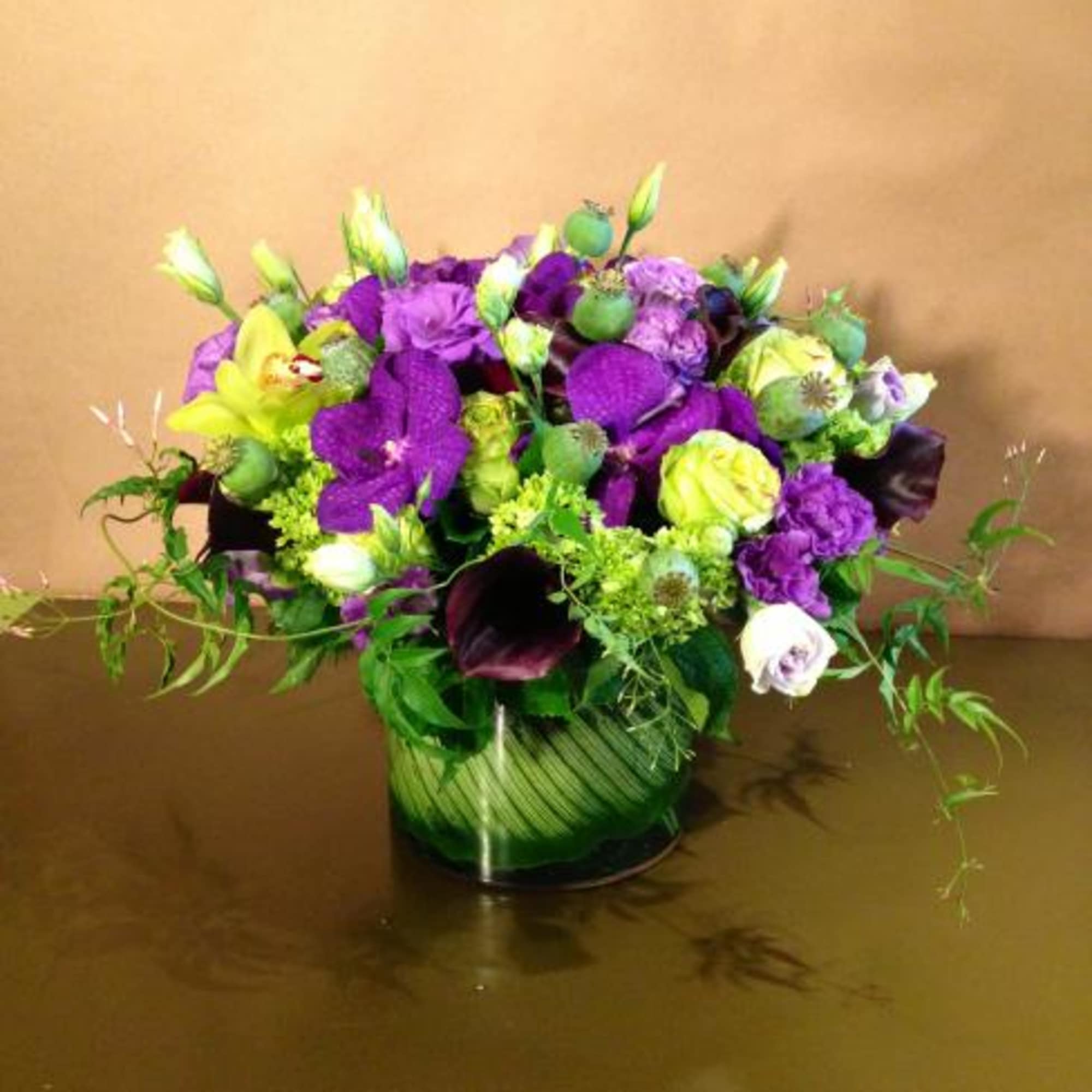 Purple and lime floral arrangement in a green glass vase