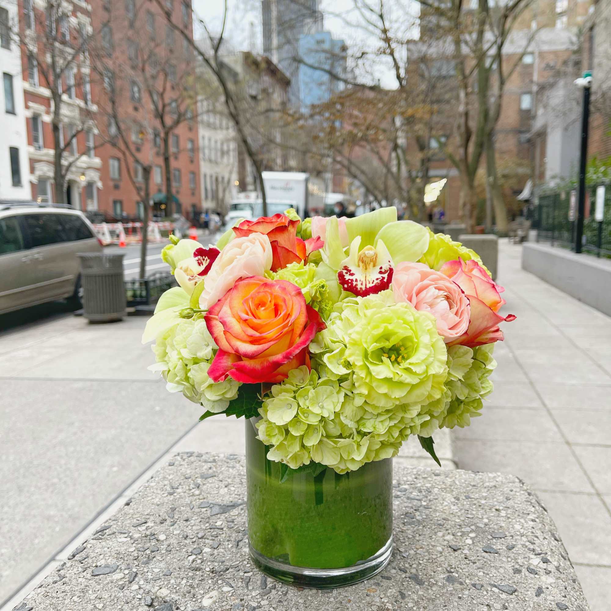Bouquet of pink and orange roses with green hydrangeas in a glass vase