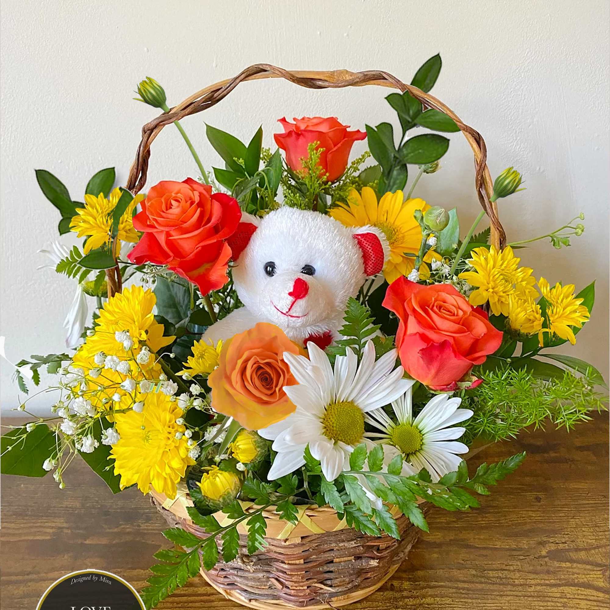 Basket arrangement of orange roses and yellow and white daisies with a small white teddy bear in the center