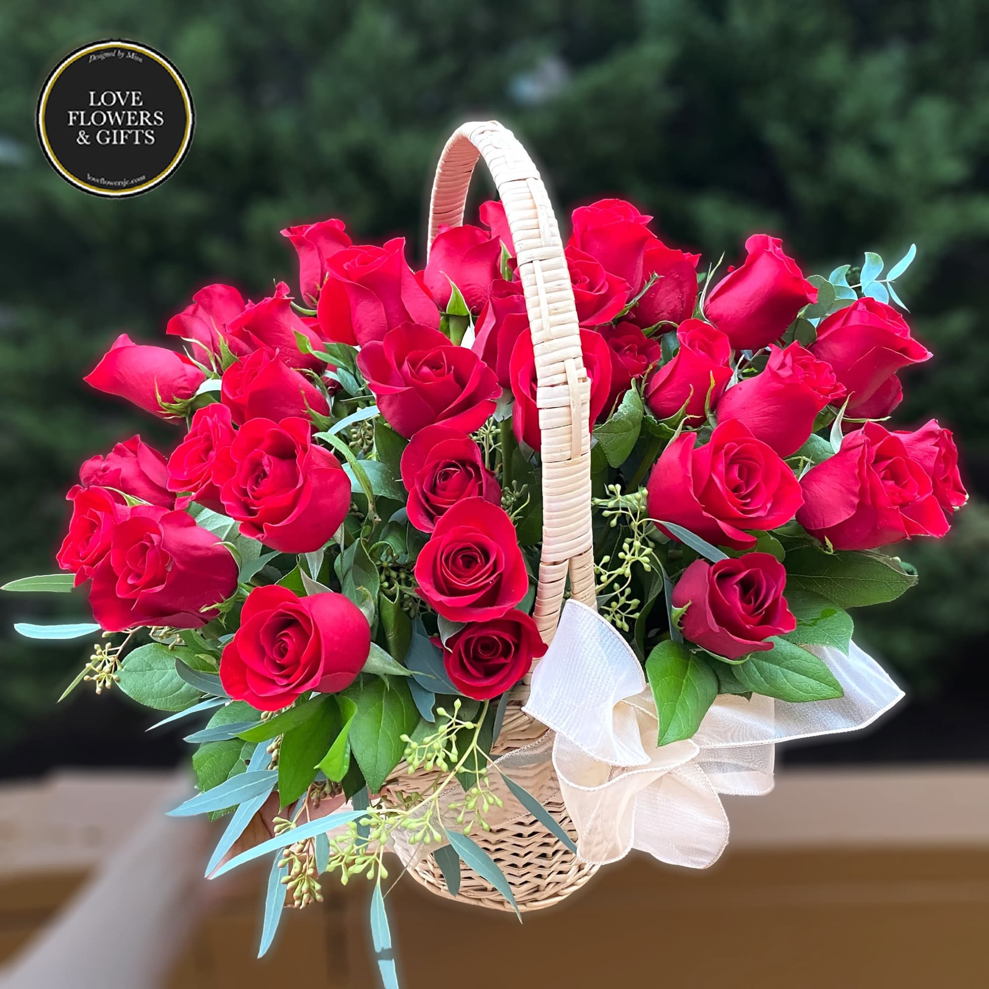 Basket of lush red roses with a white bow on the handle