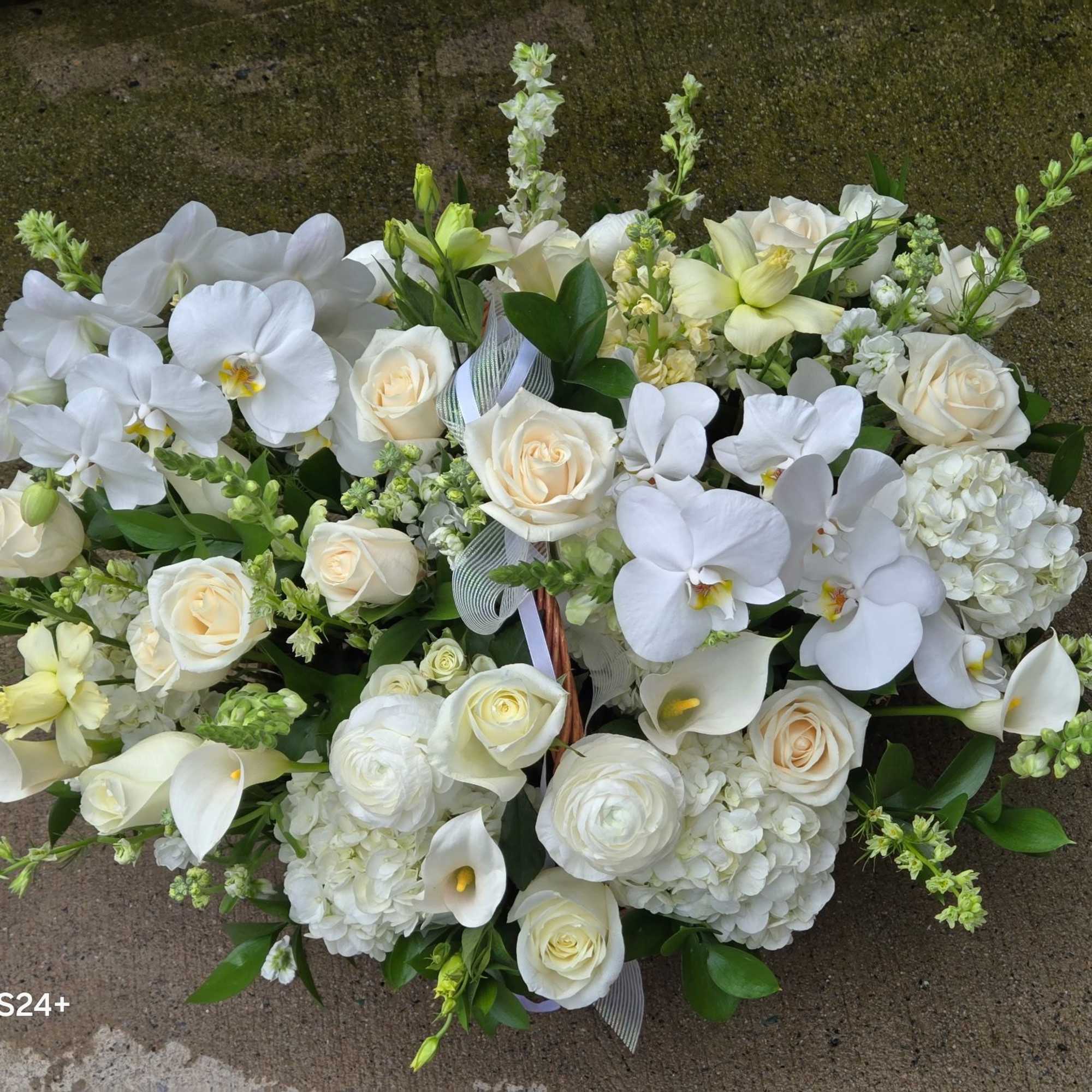 Low arrangement of white orchids, roses, hydrangeas and calla lilies in a rounded design