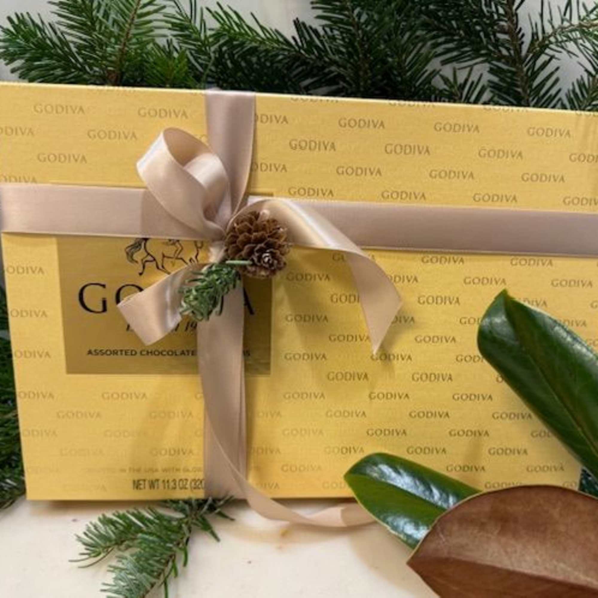 Gift box of Godiva assorted chocolates tied with a ribbon and pine sprig