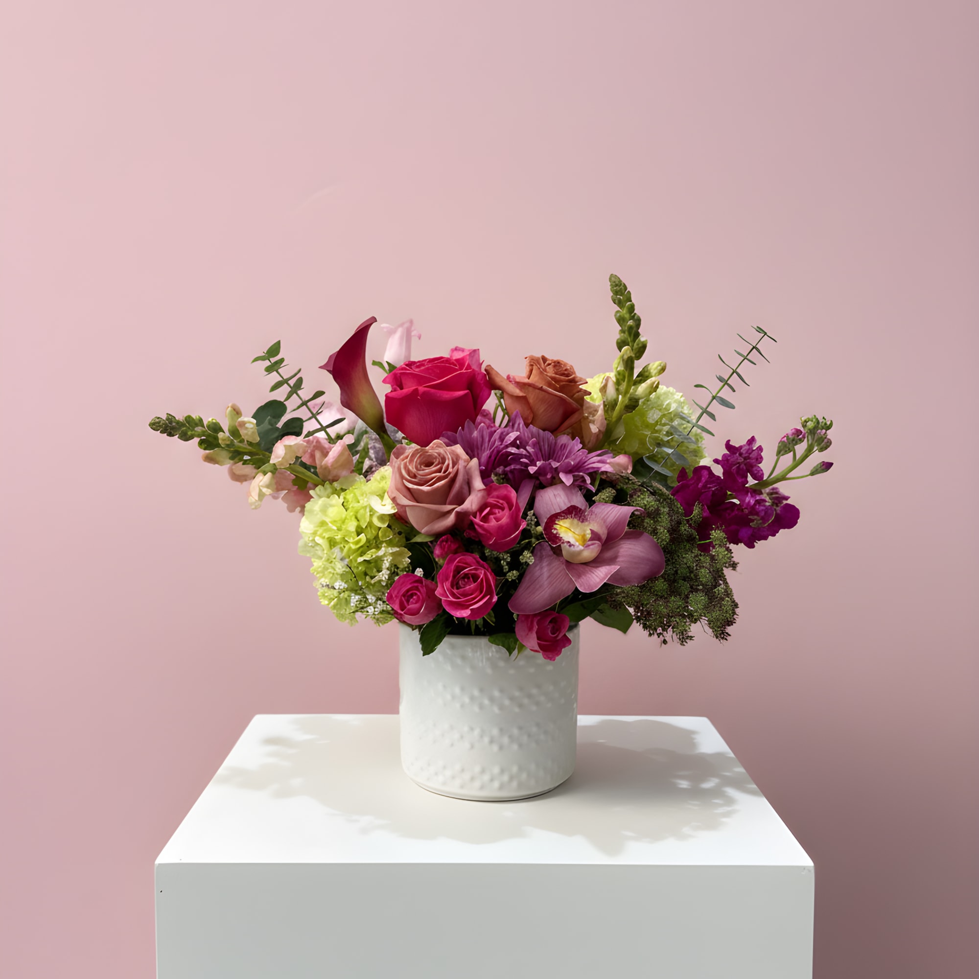 Mixed pink and purple flower arrangement in a white vase