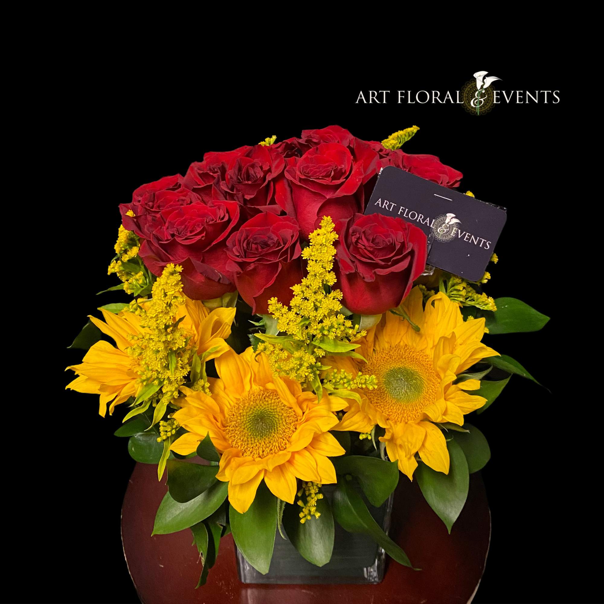 Red roses and yellow sunflowers in a square vase