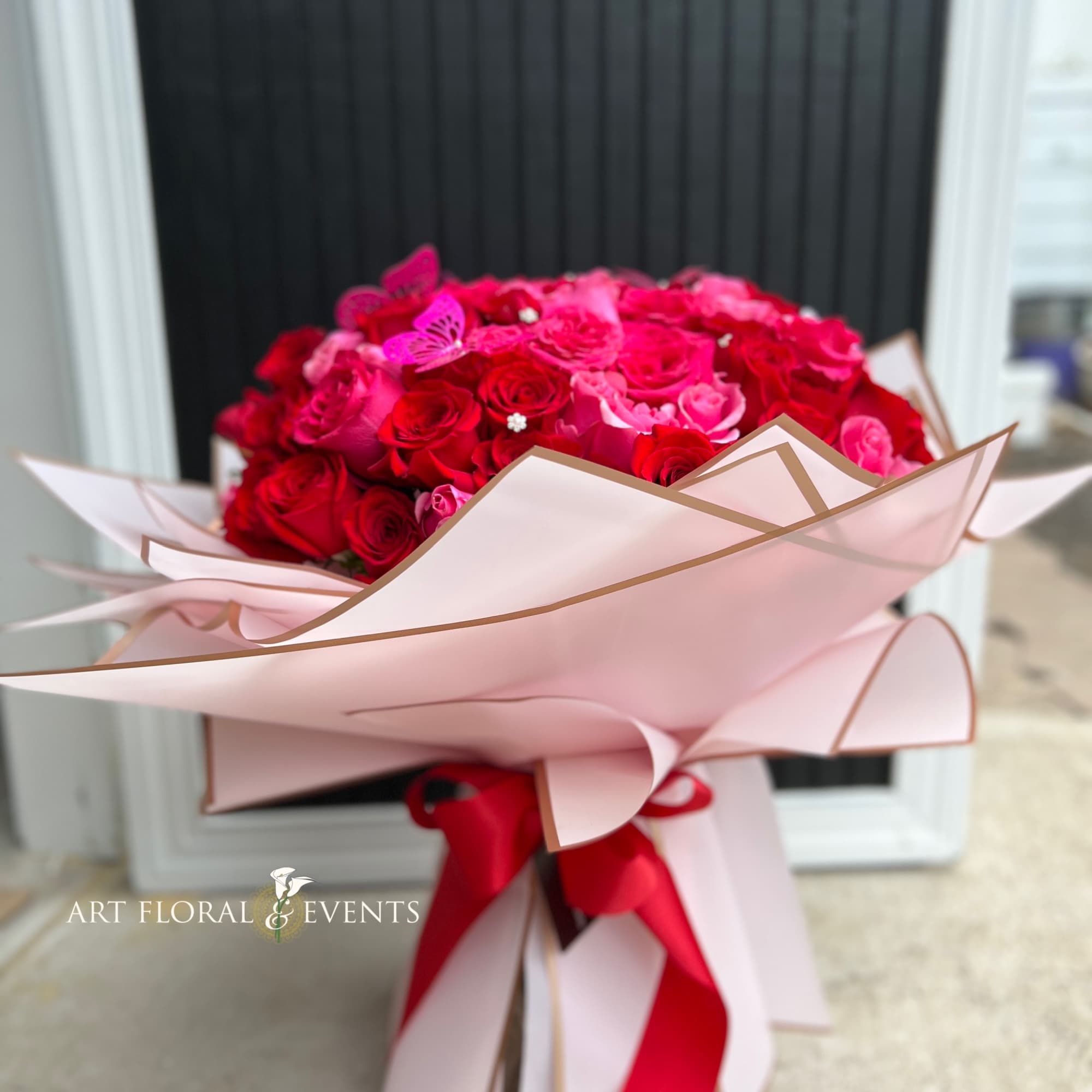 Bouquet of red and pink roses wrapped in pale pink paper with a red ribbon