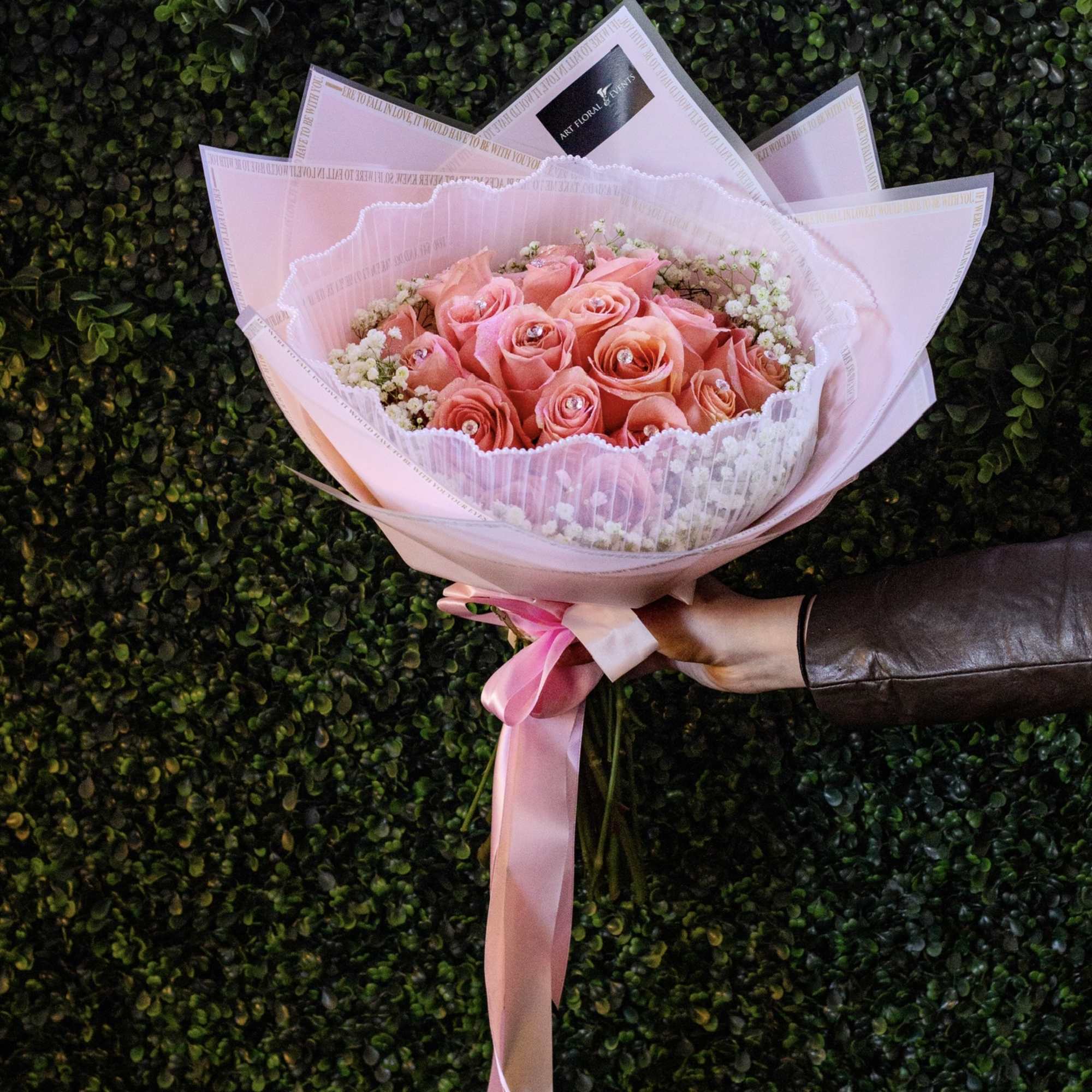 Pink rose bouquet wrapped in pale pink paper with a ribbon