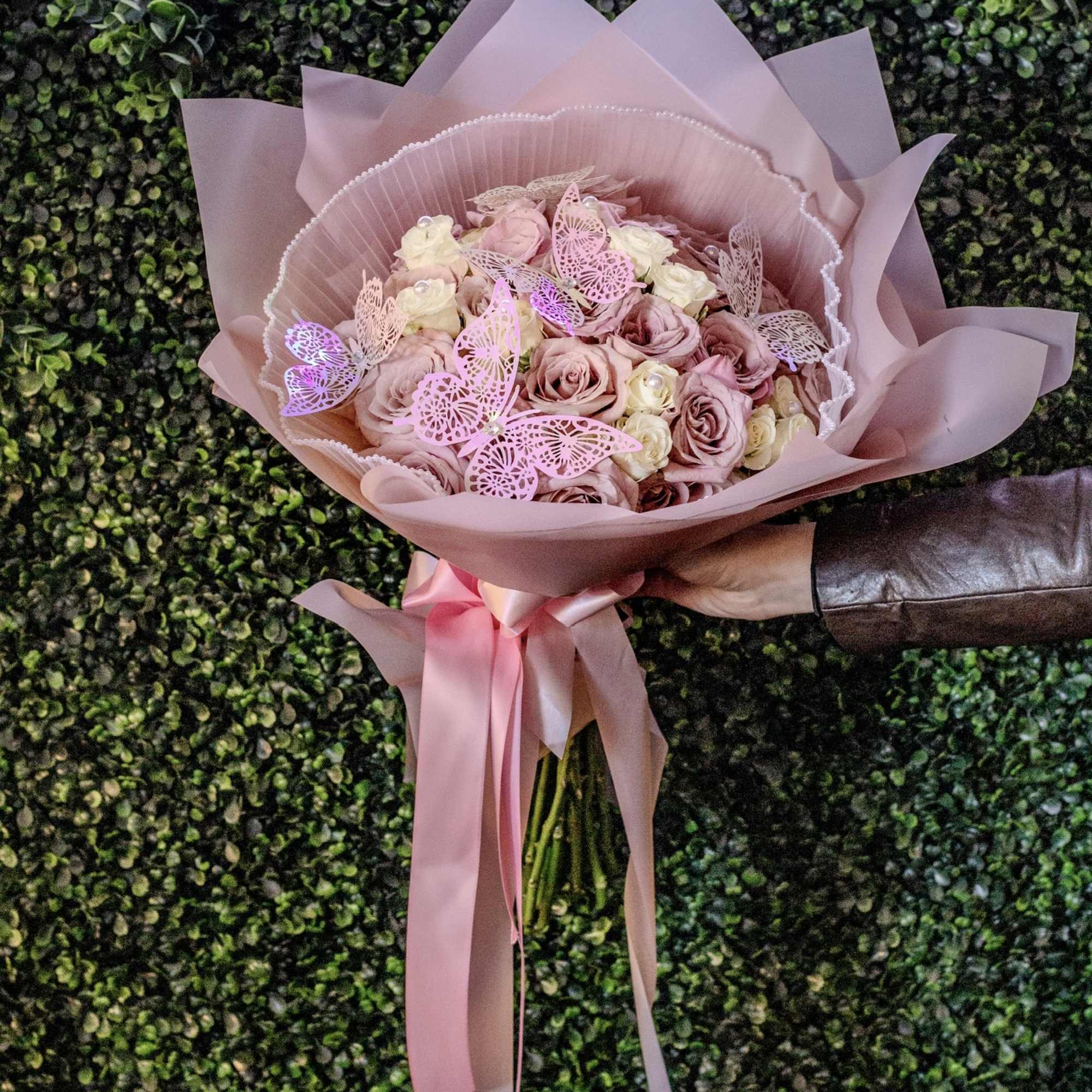 Pink rose bouquet wrapped in blush paper with a satin ribbon