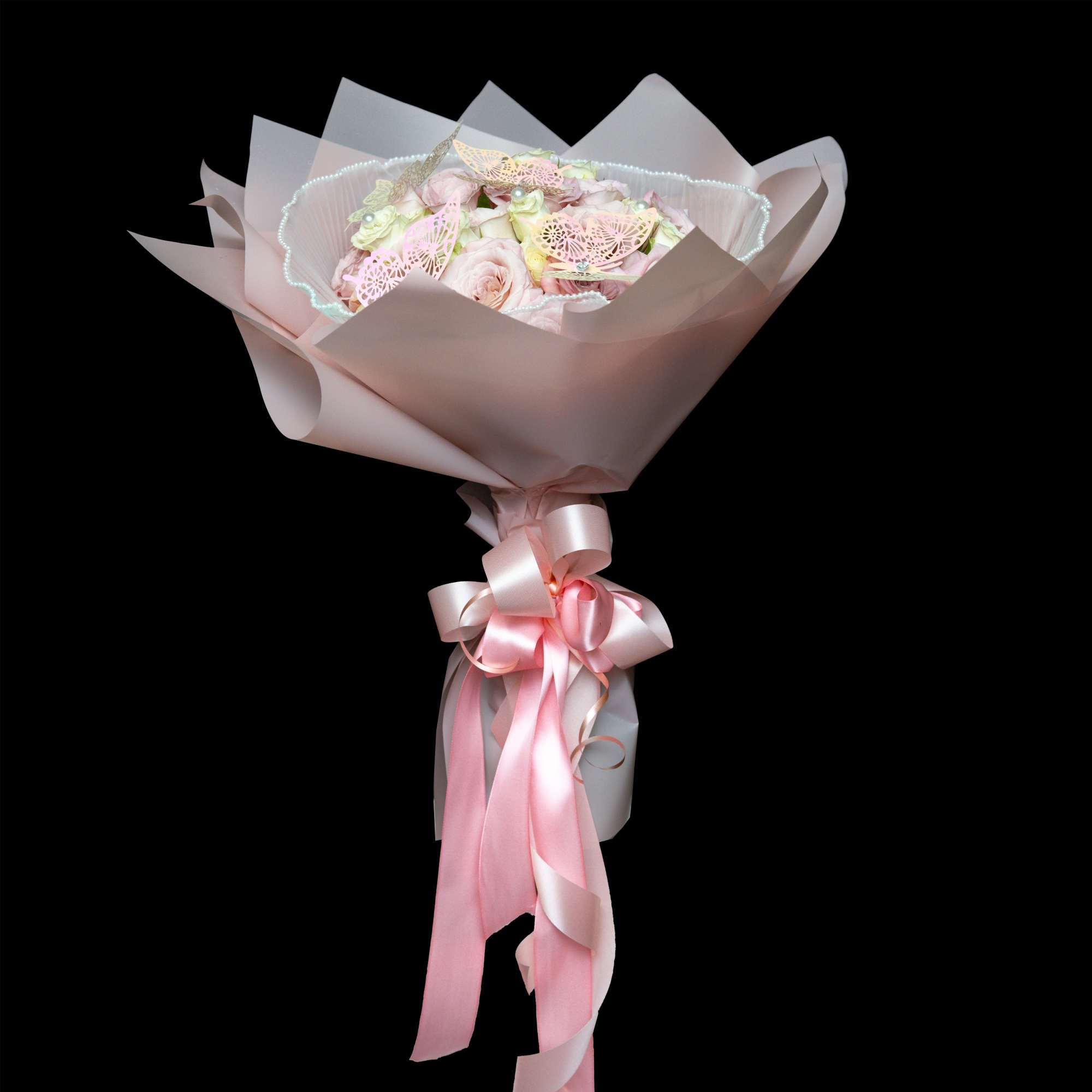 Pink rose bouquet wrapped in pale paper with a satin ribbon