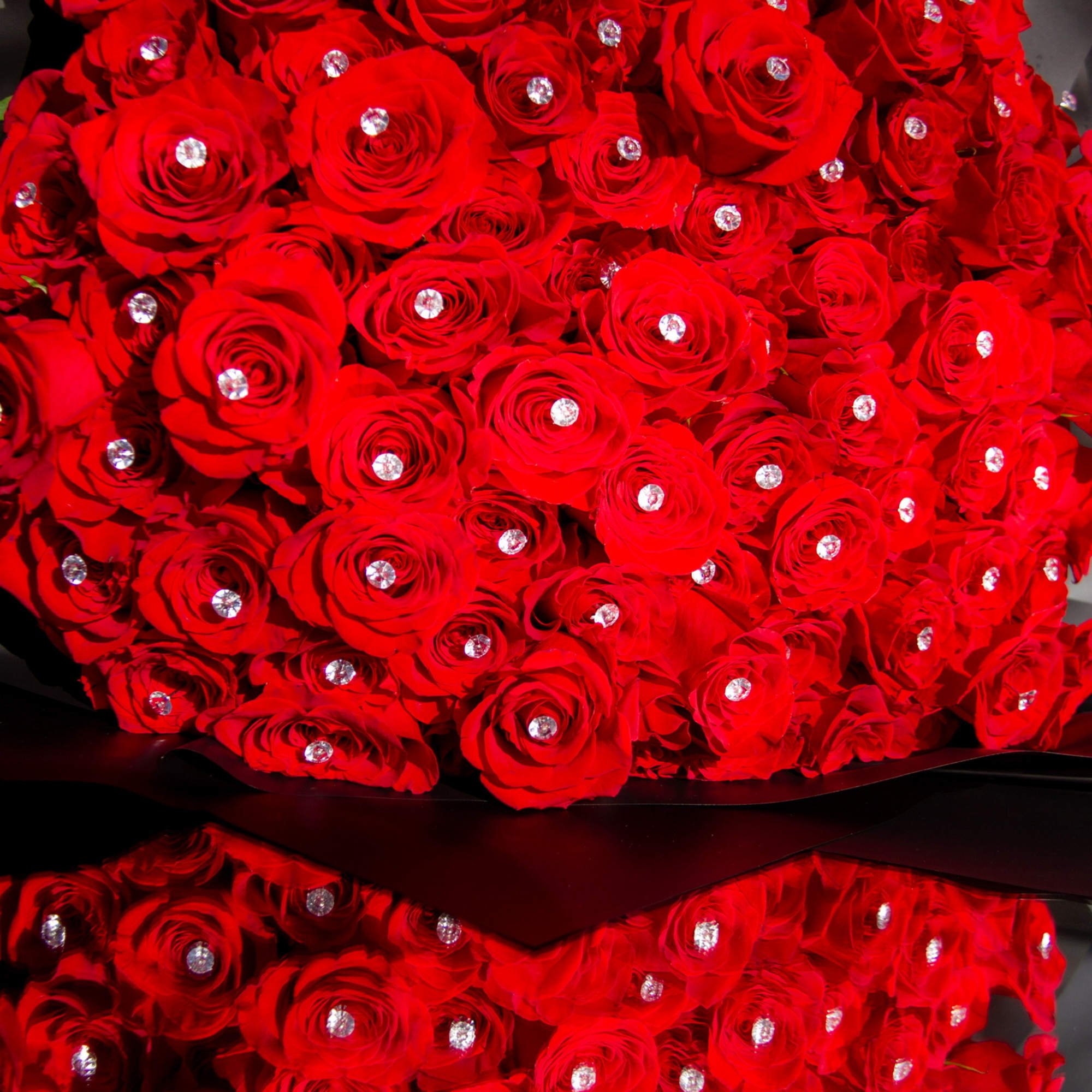 Bouquet of red roses with jeweled centers wrapped in dark paper