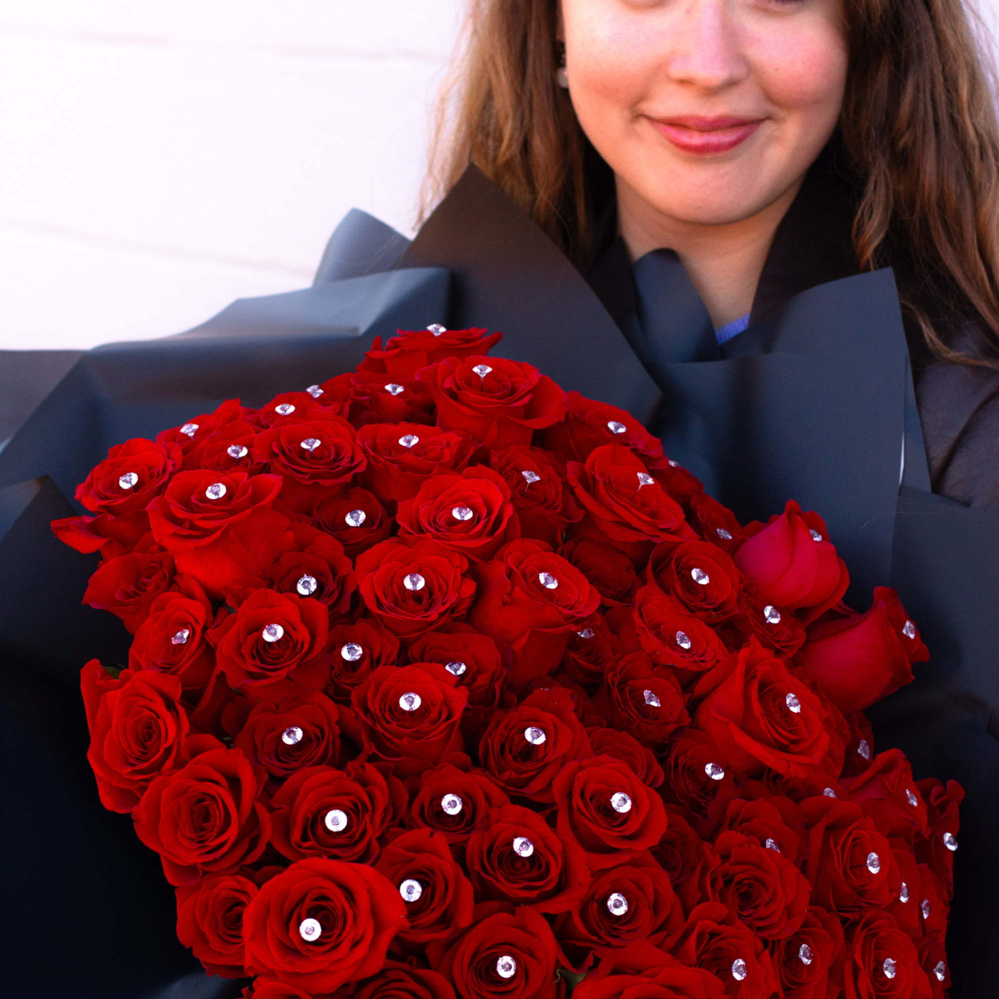 Woman holding a large bouquet of red roses with jeweled accents