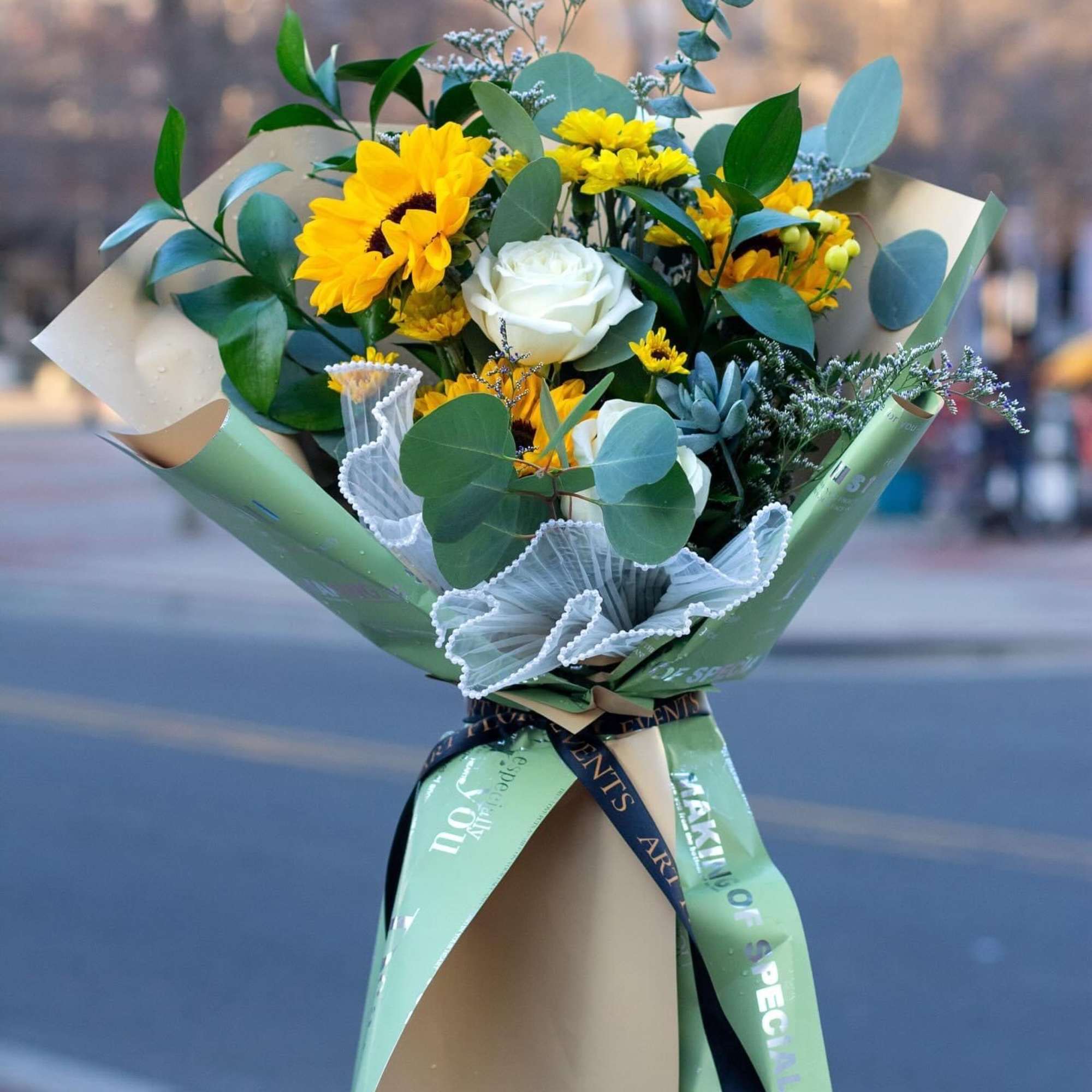 Bouquet of yellow sunflowers and white roses wrapped in paper