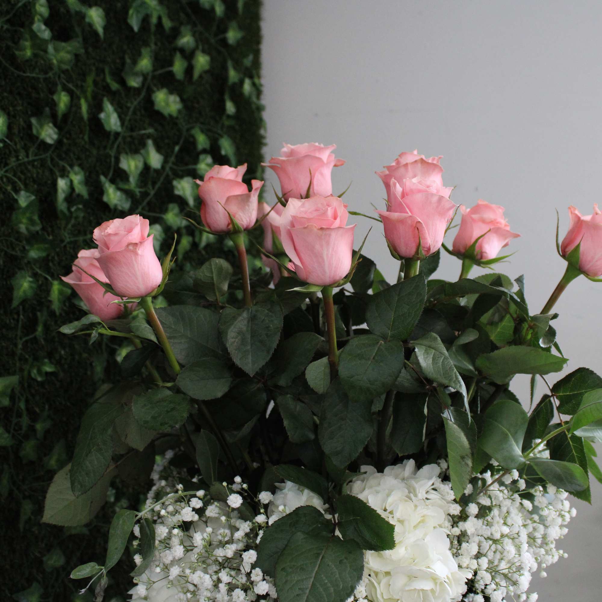 Pink roses arranged above white flowers in a vase