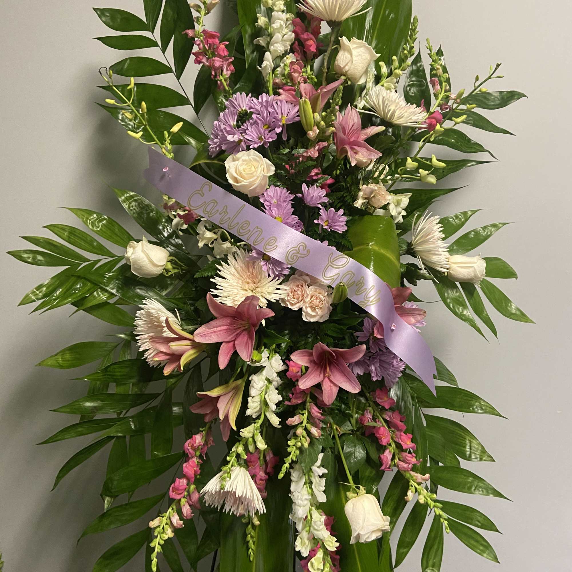 Standing floral spray with pink and white flowers and a lavender ribbon