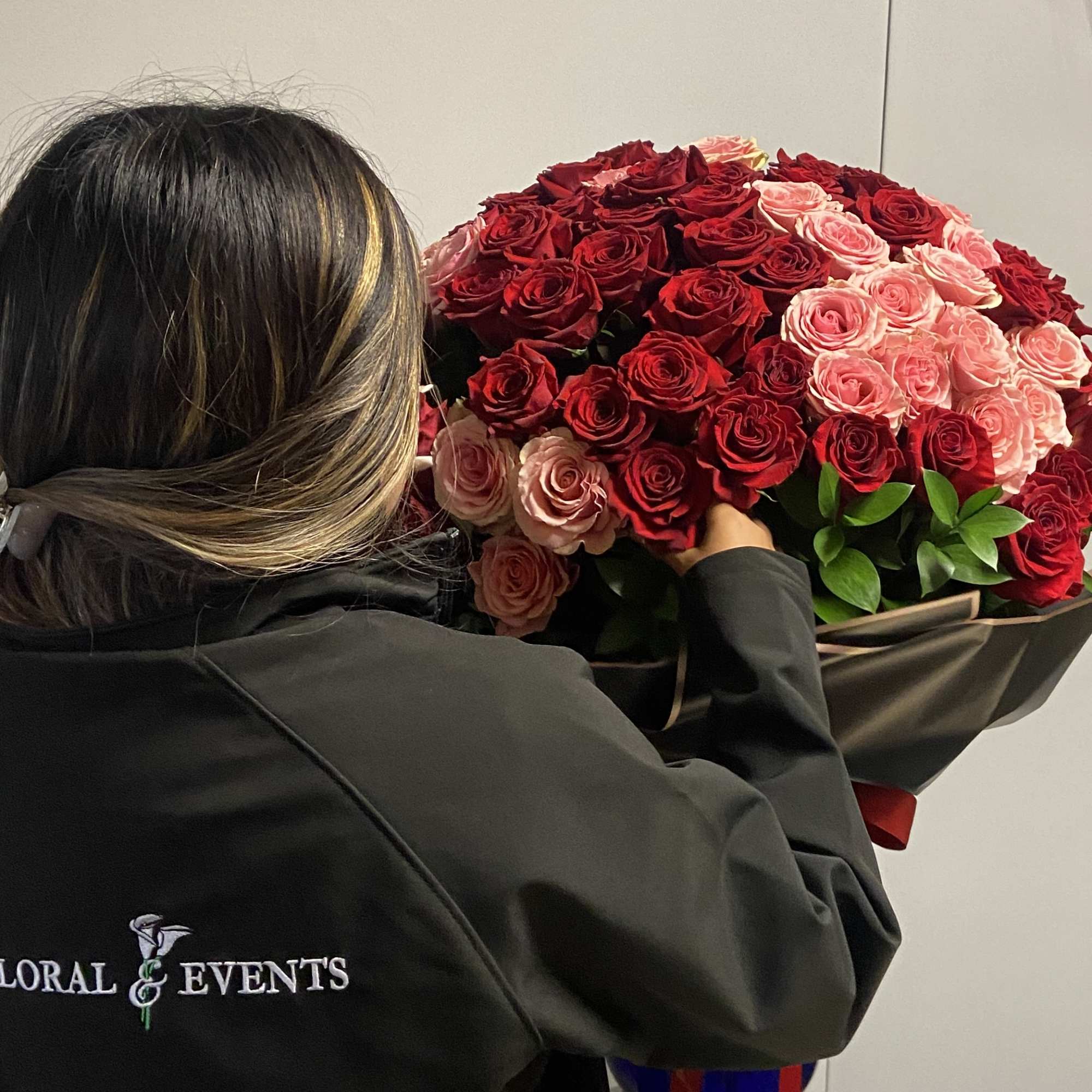 Large bouquet of red and pink roses wrapped in dark paper