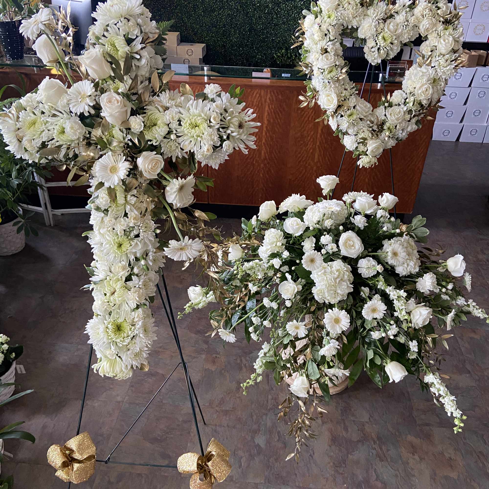 White floral funeral sprays and a heart-shaped wreath on stands