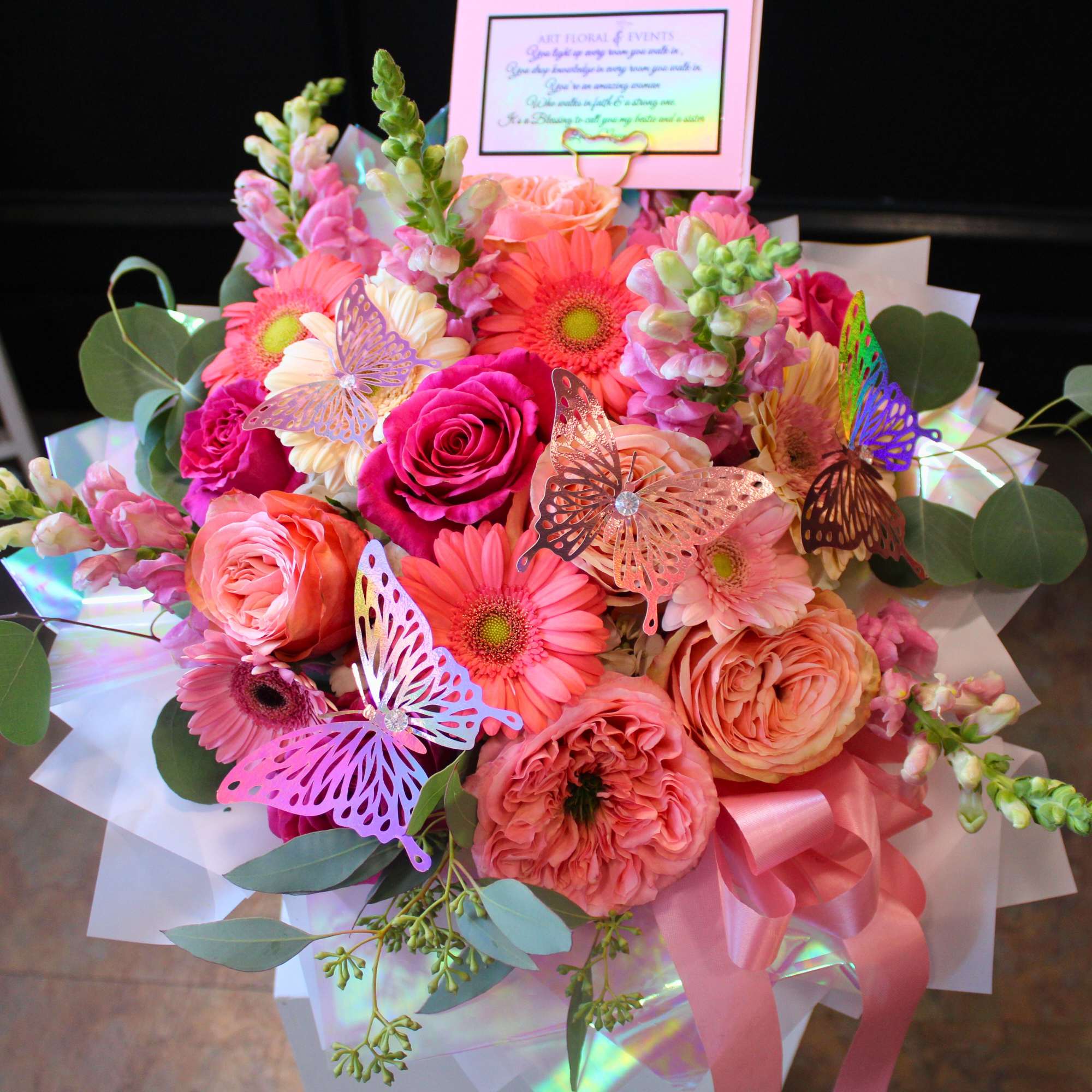 Bright mixed bouquet of pink and peach flowers with butterfly decorations