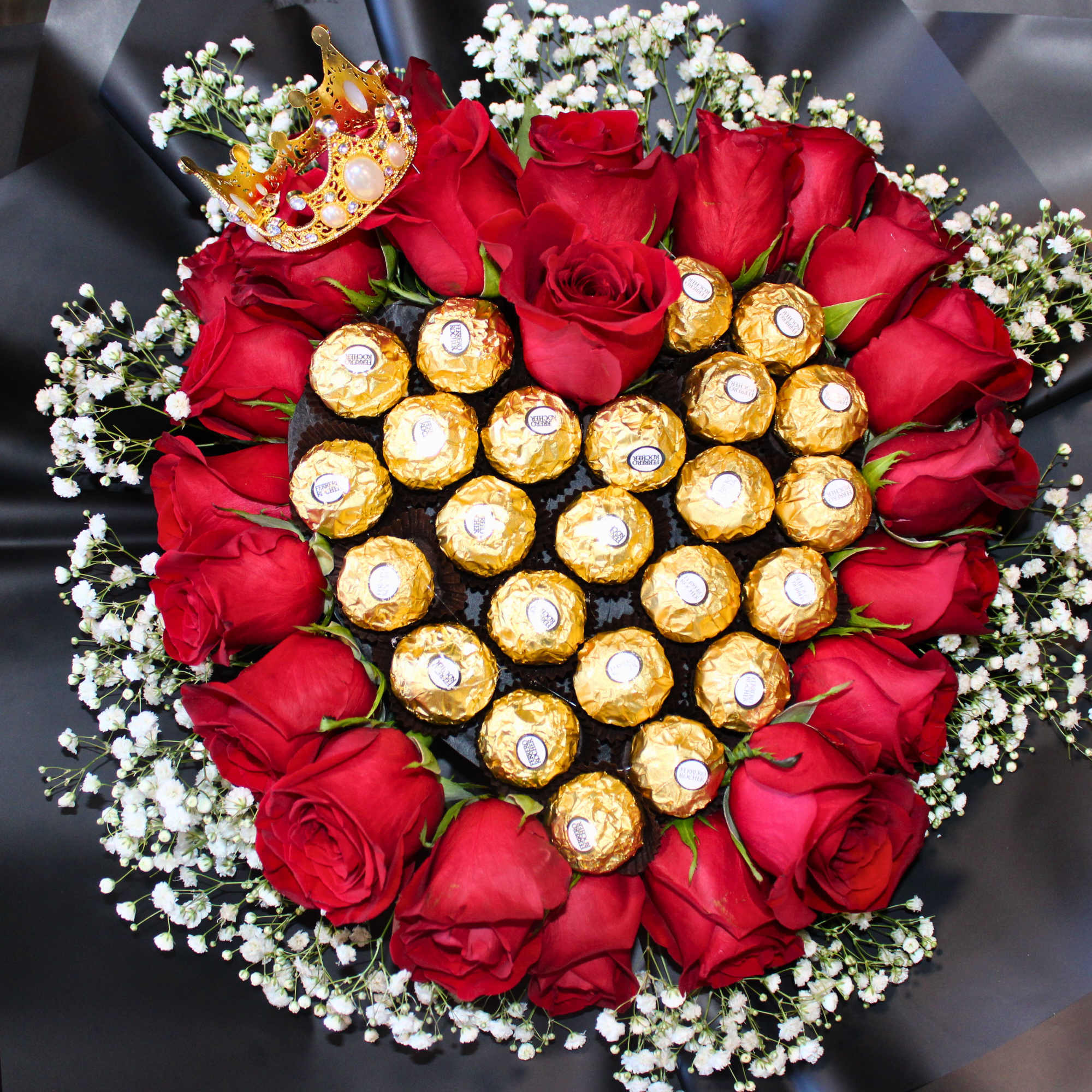 Heart-shaped bouquet of red roses with gold-wrapped chocolates and a small crown