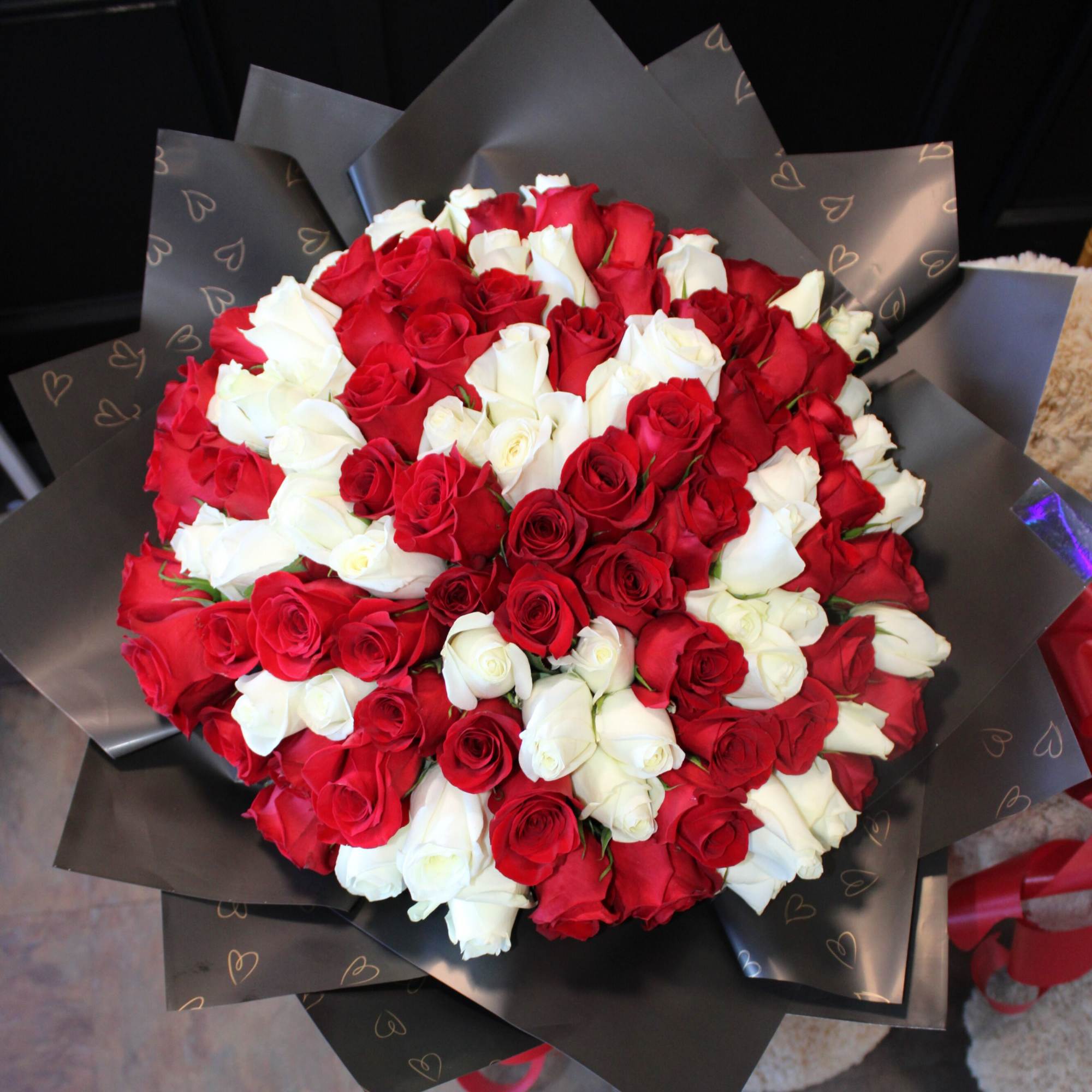 Large bouquet of red and white roses wrapped in black paper