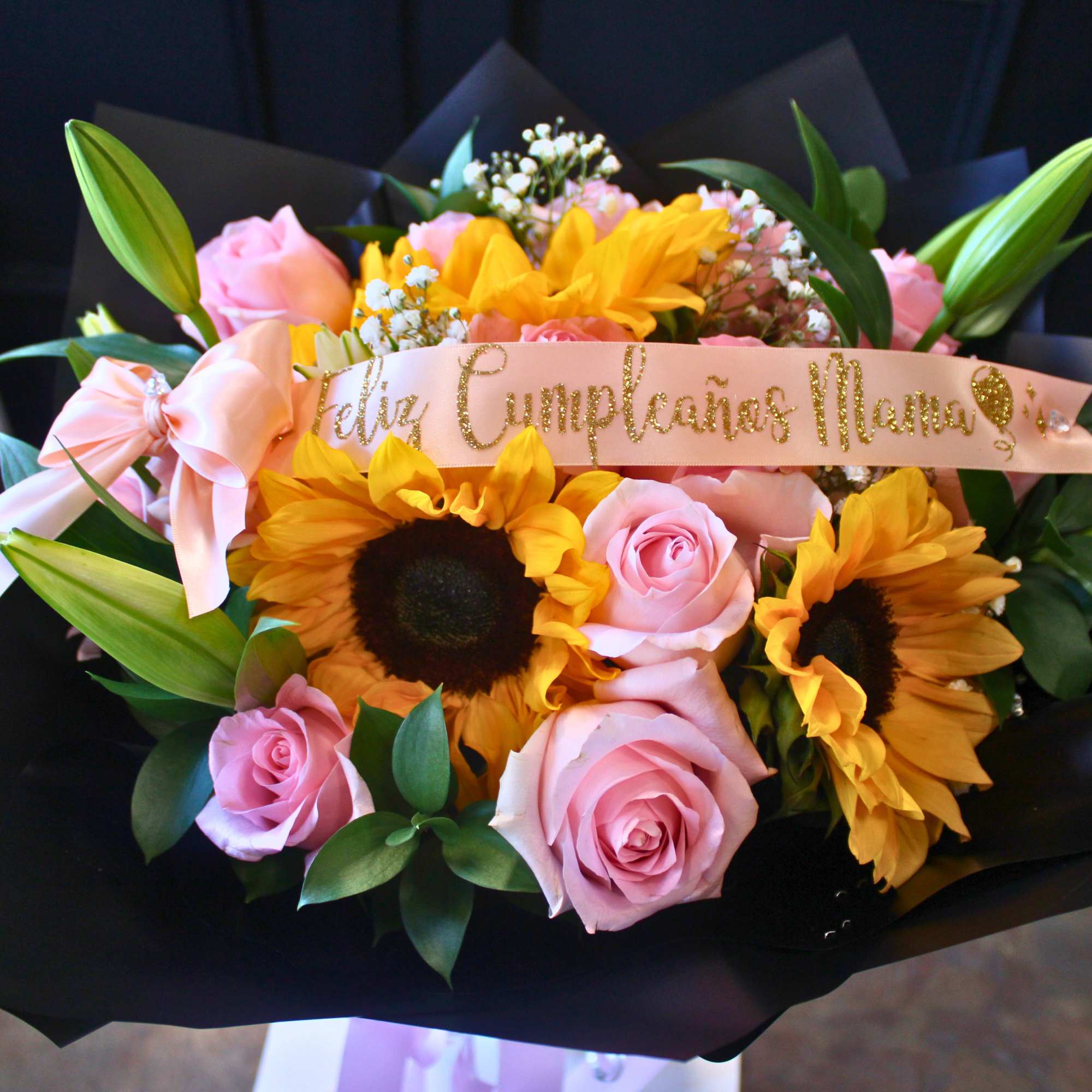 Bouquet of pink roses and yellow sunflowers with a ribbon banner