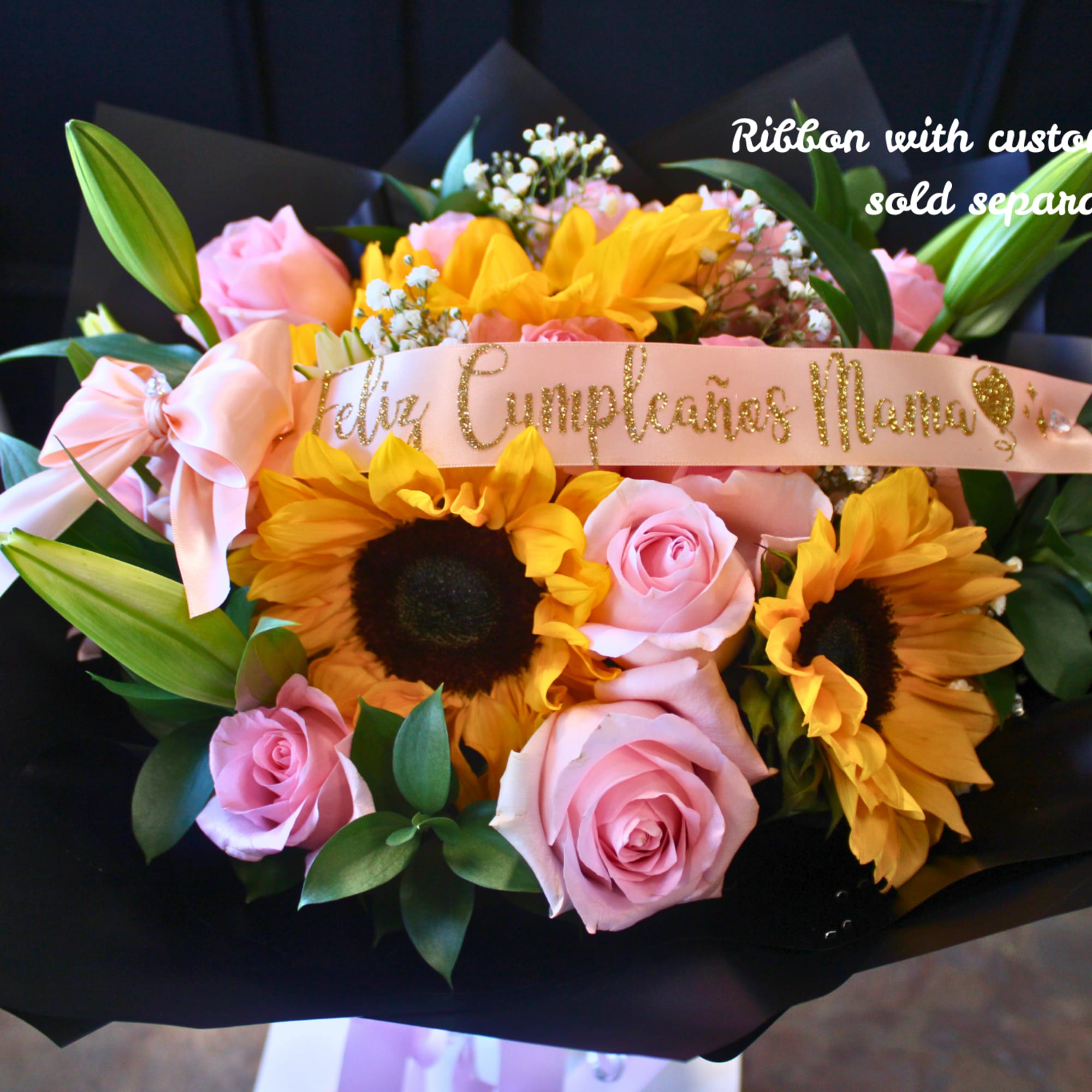 Bouquet of pink roses and sunflowers wrapped in black paper with a pink ribbon