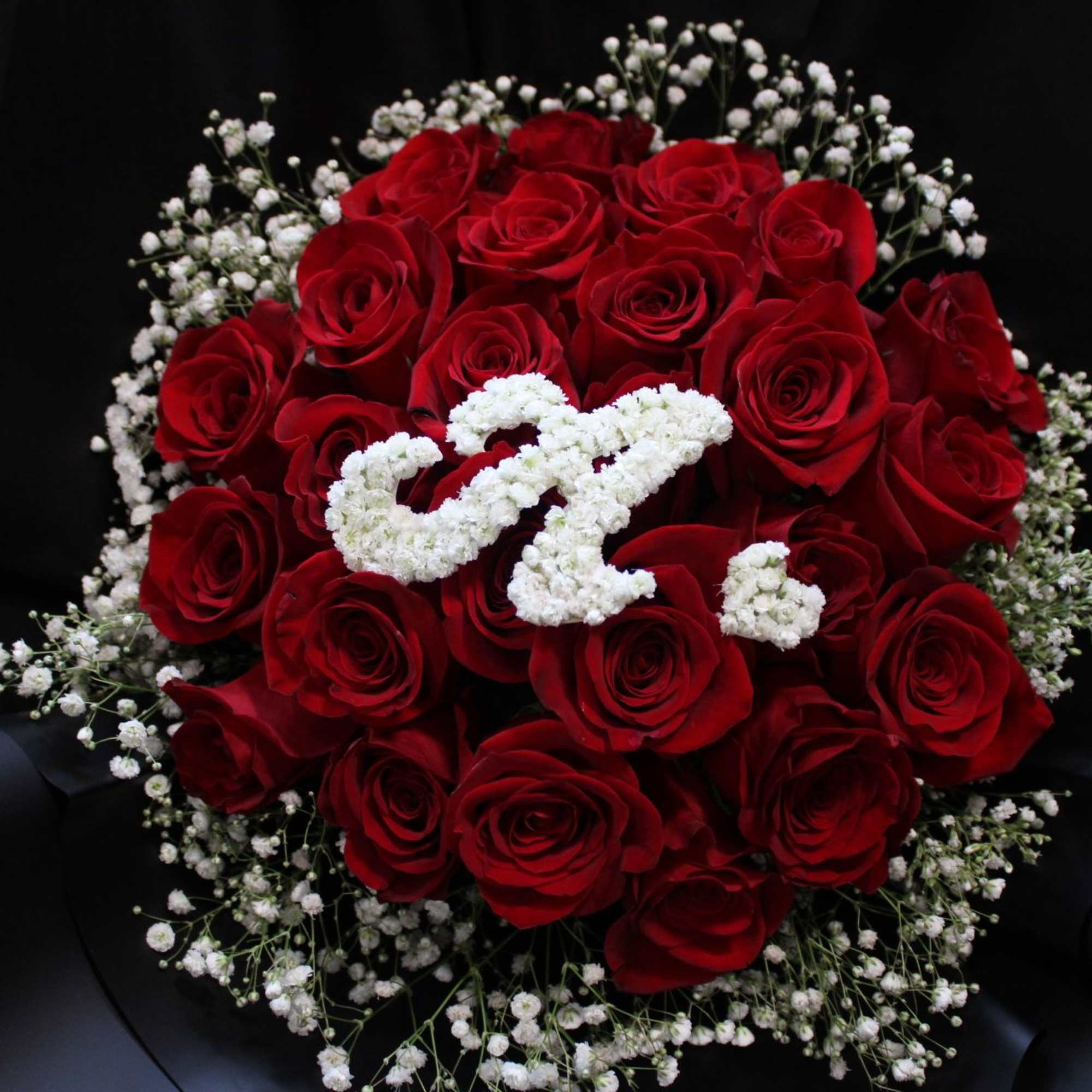 Bouquet of red roses with white baby's breath on black wrapping