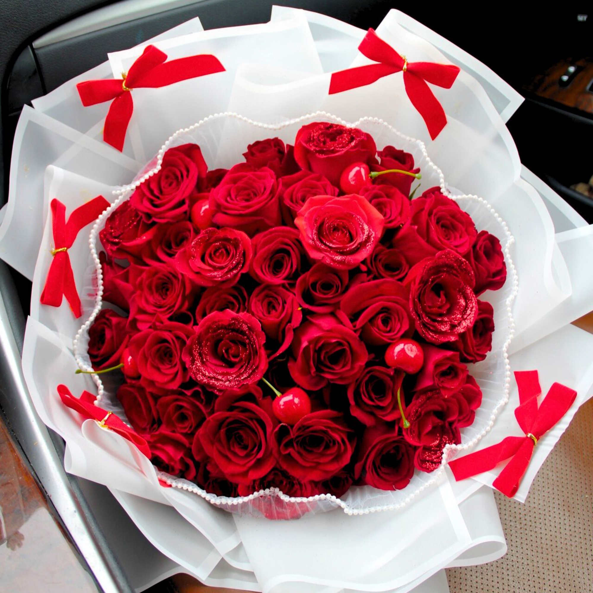 Bouquet of red roses wrapped in white paper with red bows, photo 2 of 2