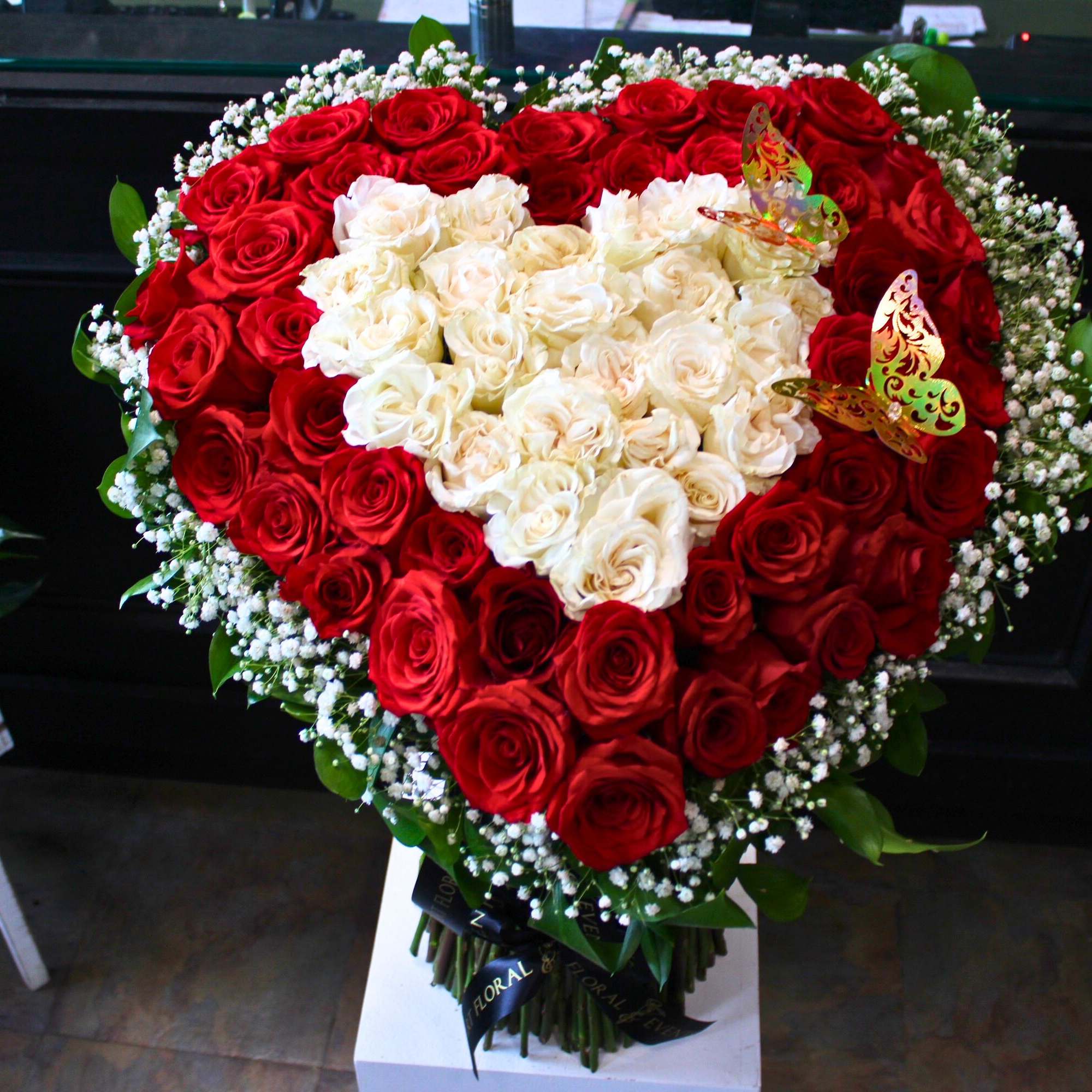 Heart-shaped bouquet of red and white roses with butterfly accents
