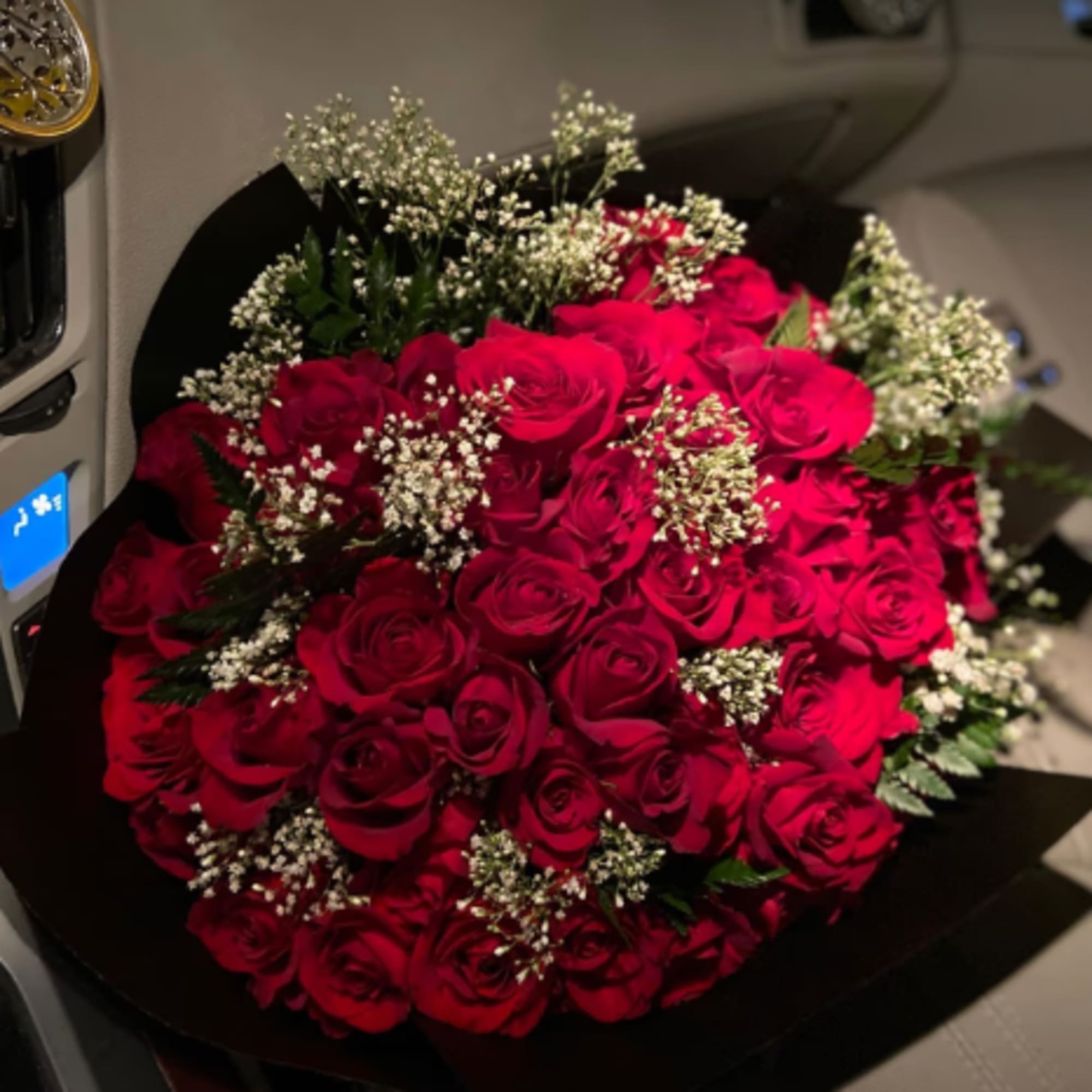 Bouquet of red roses with white filler flowers wrapped in black paper