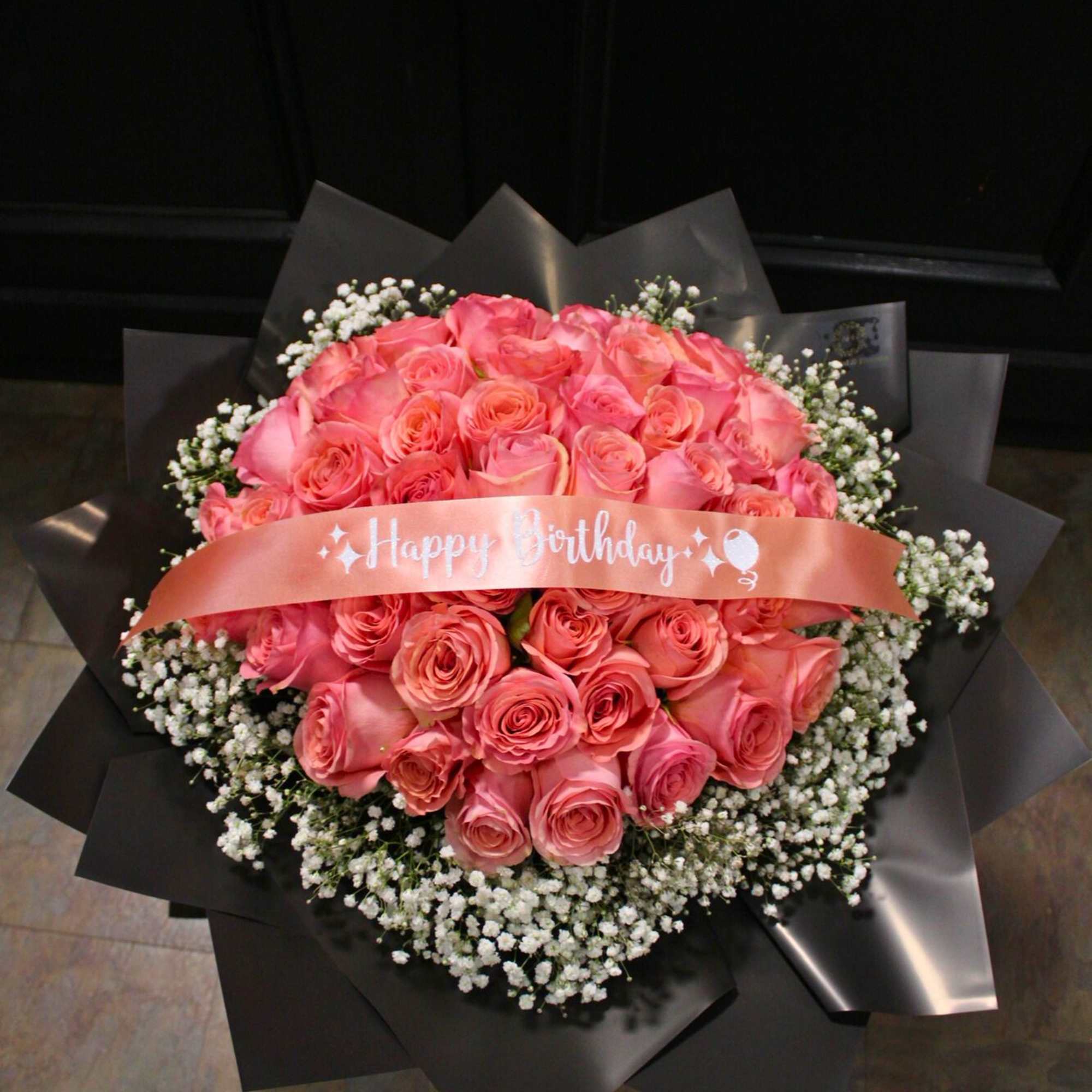 Pink rose bouquet with a birthday ribbon and black wrapping
