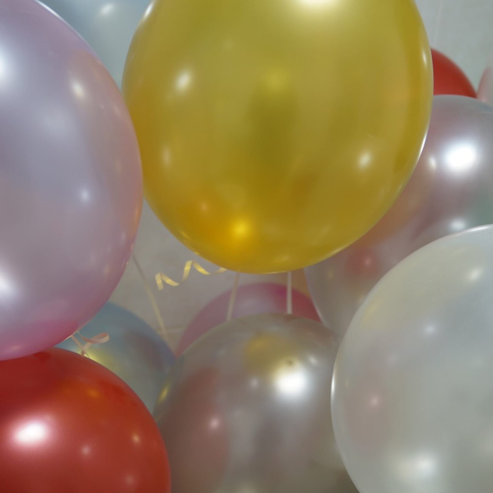 Cluster of pastel and metallic balloons in yellow, white, pink, and red tones