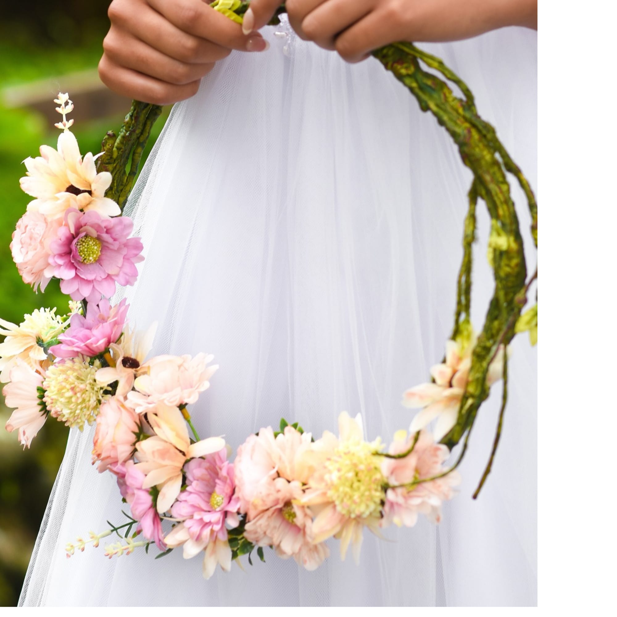Person holding a floral wreath with pink and cream flowers