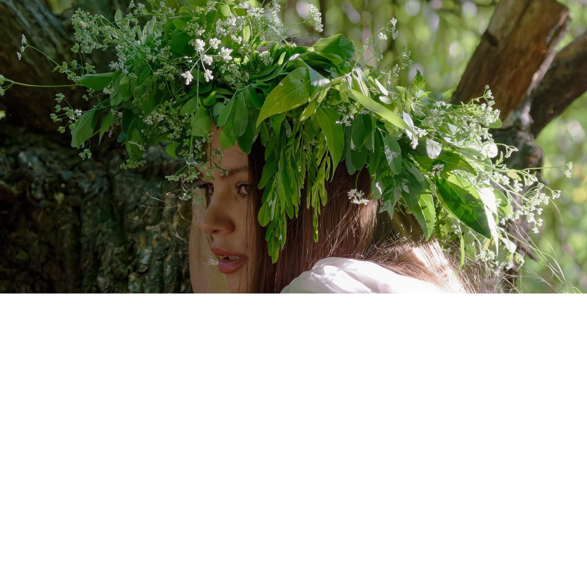 Woman wearing a leafy floral crown with small white blossoms
