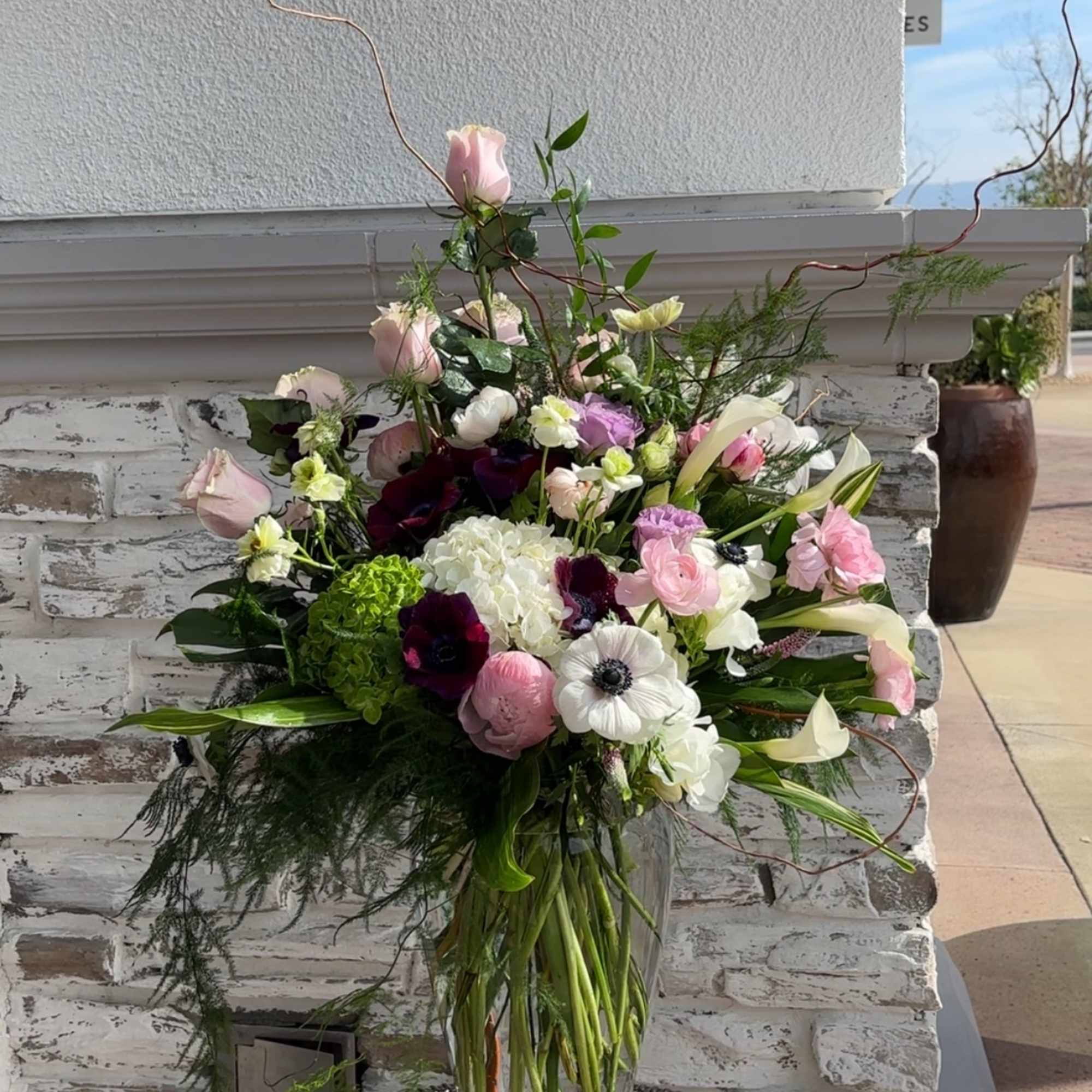 Tall mixed bouquet in a clear glass vase with pink, white, and purple blooms