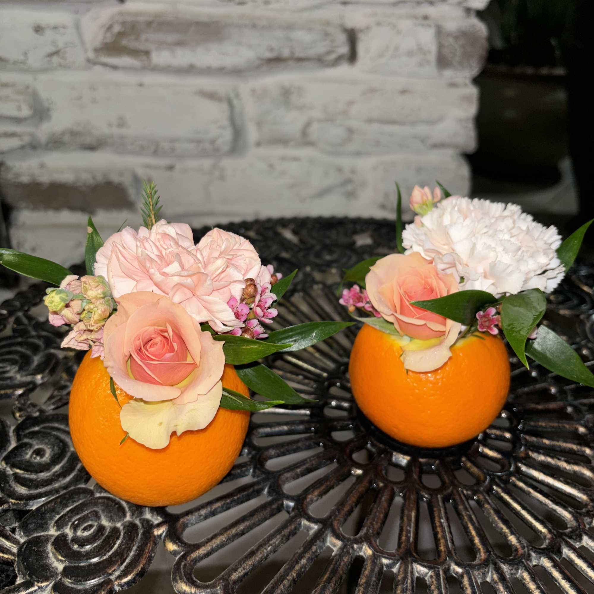 Two small floral arrangements in orange halves on a table