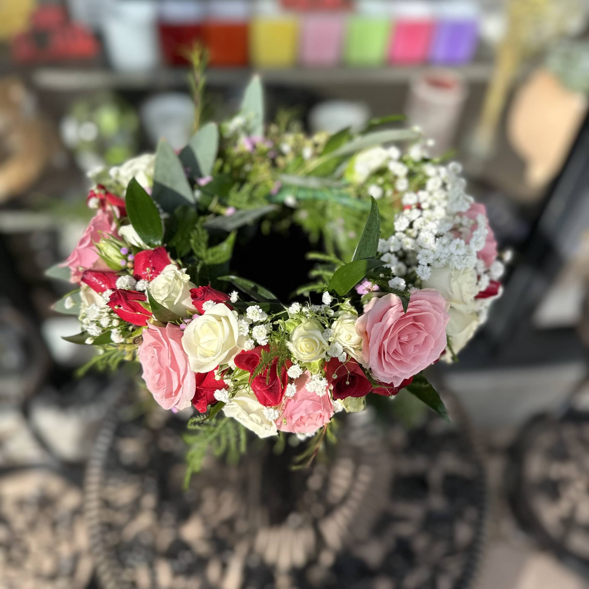 Circular wreath of pink, red, and white roses with baby's breath