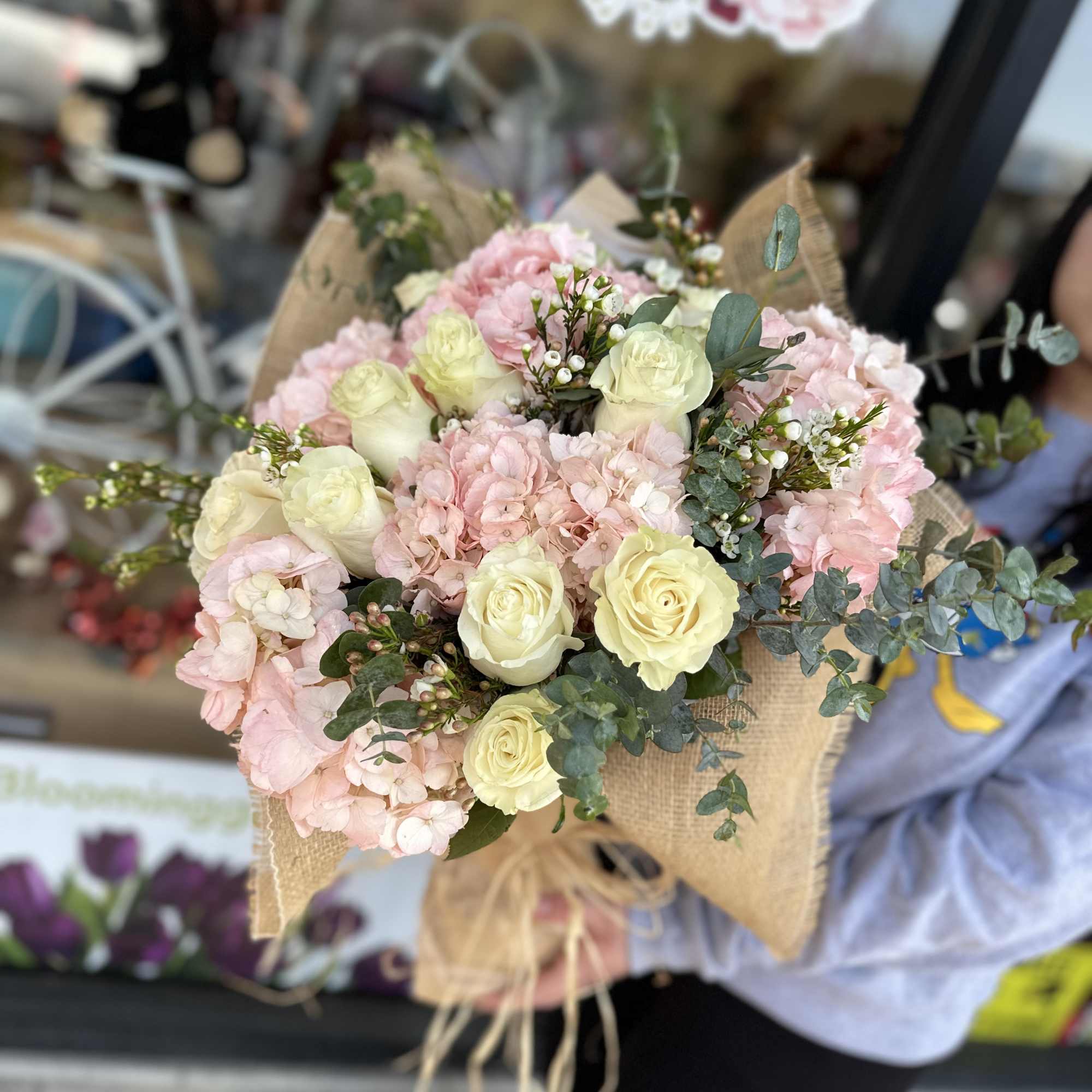 Bouquet of pale pink hydrangeas and cream roses wrapped in burlap
