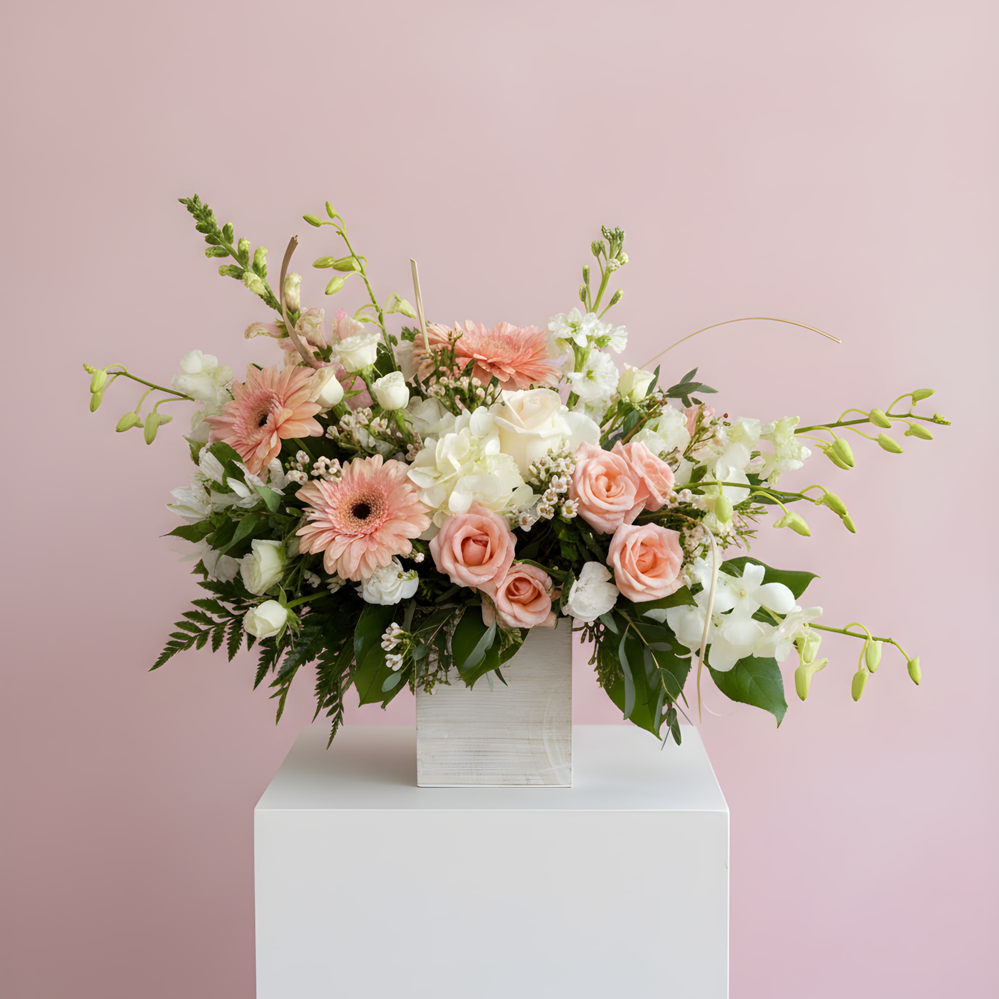 Peach and white floral arrangement in a square white vase