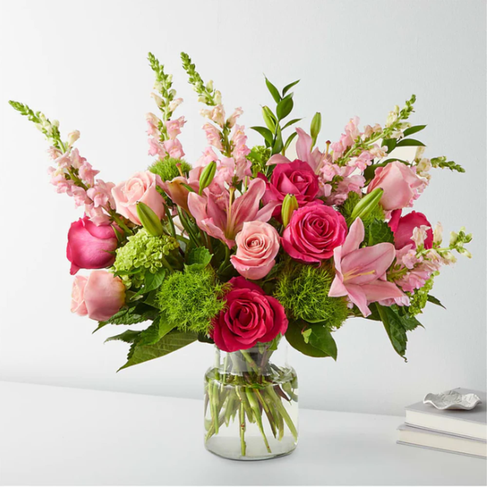 Pink roses and lilies arranged in a clear glass vase