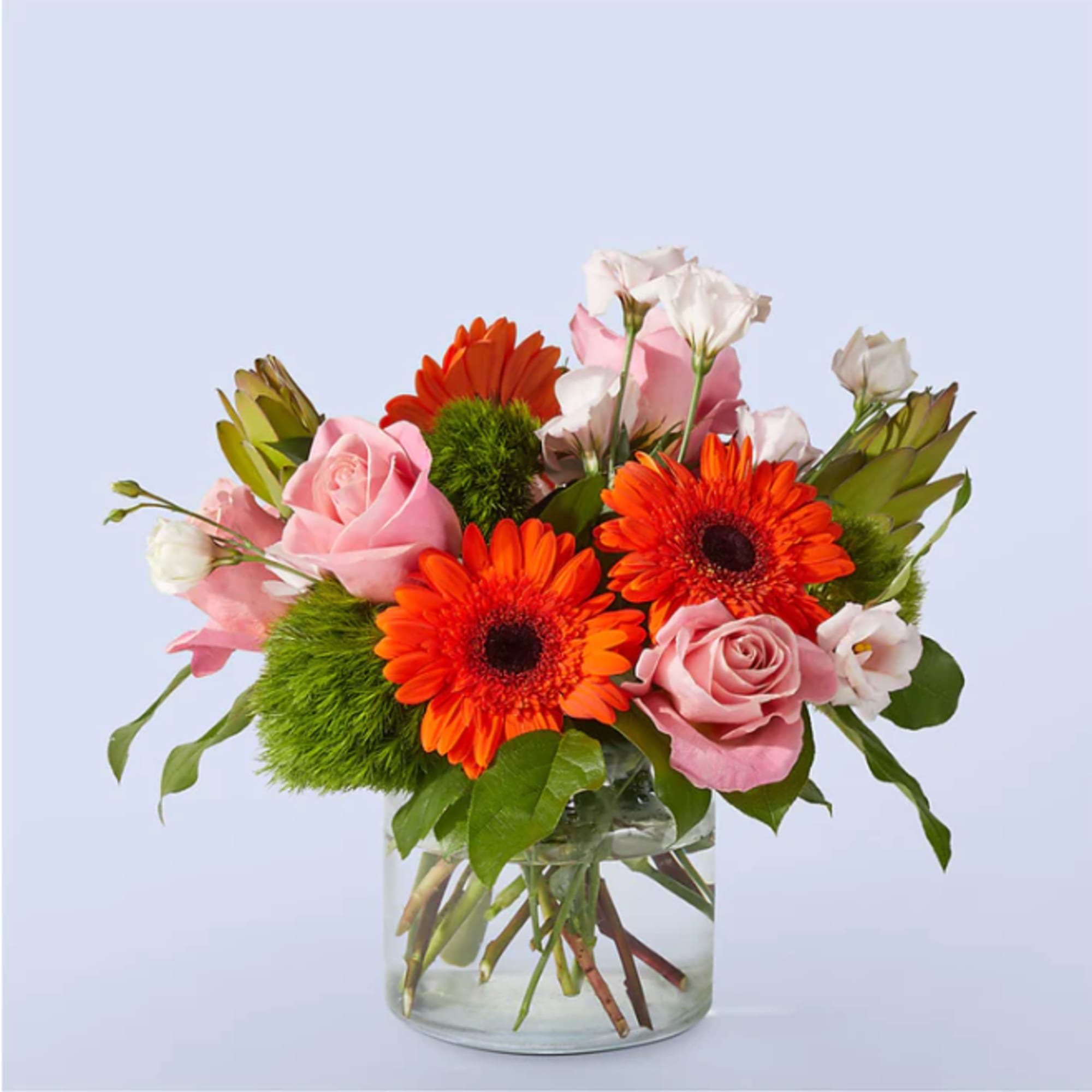 Pink roses and orange gerbera daisies in a clear glass vase