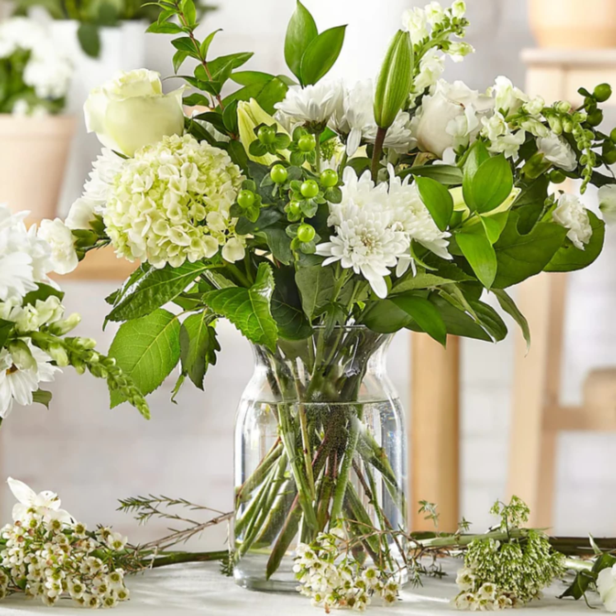 White flowers arranged in a clear glass vase with green foliage