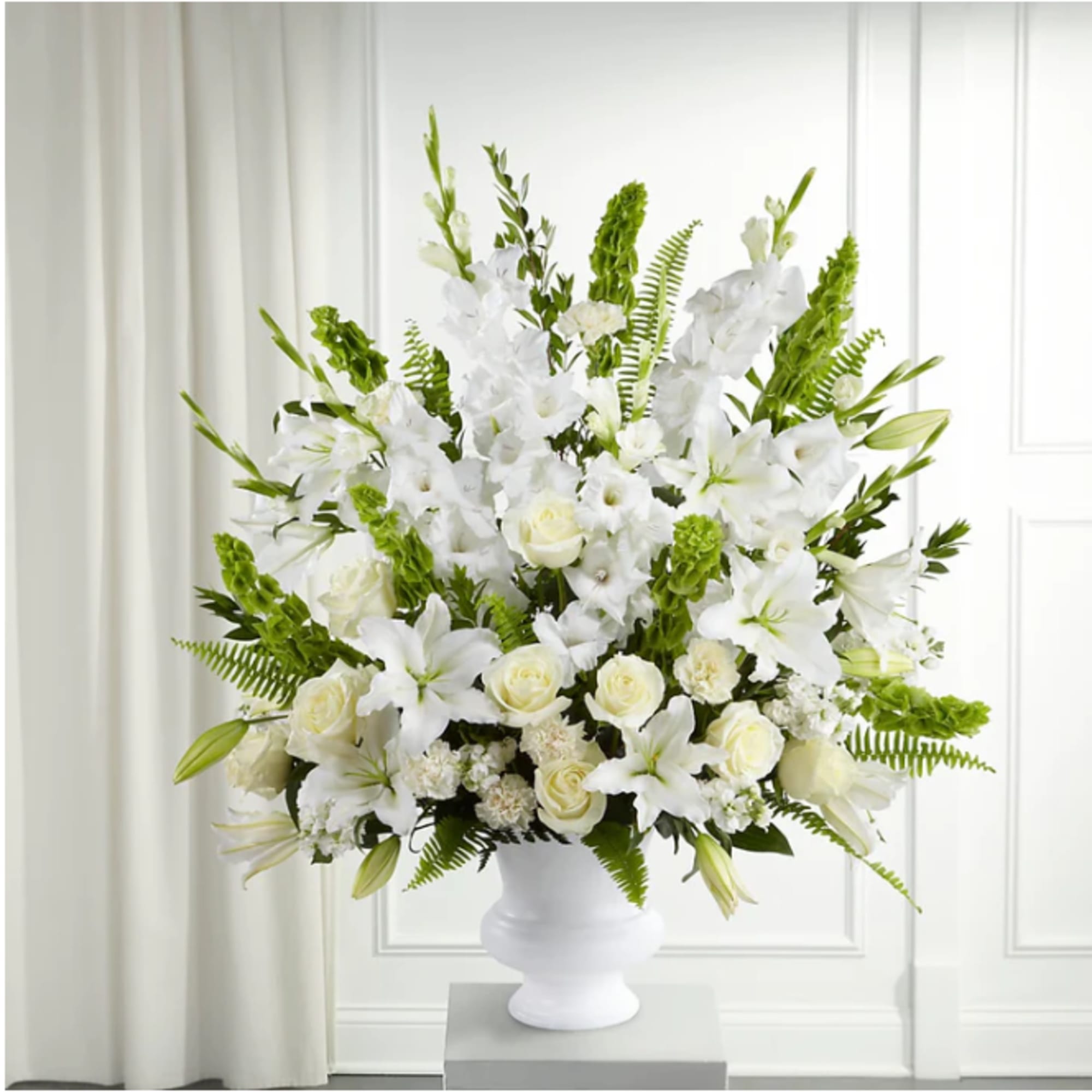 White floral arrangement in a white urn vase