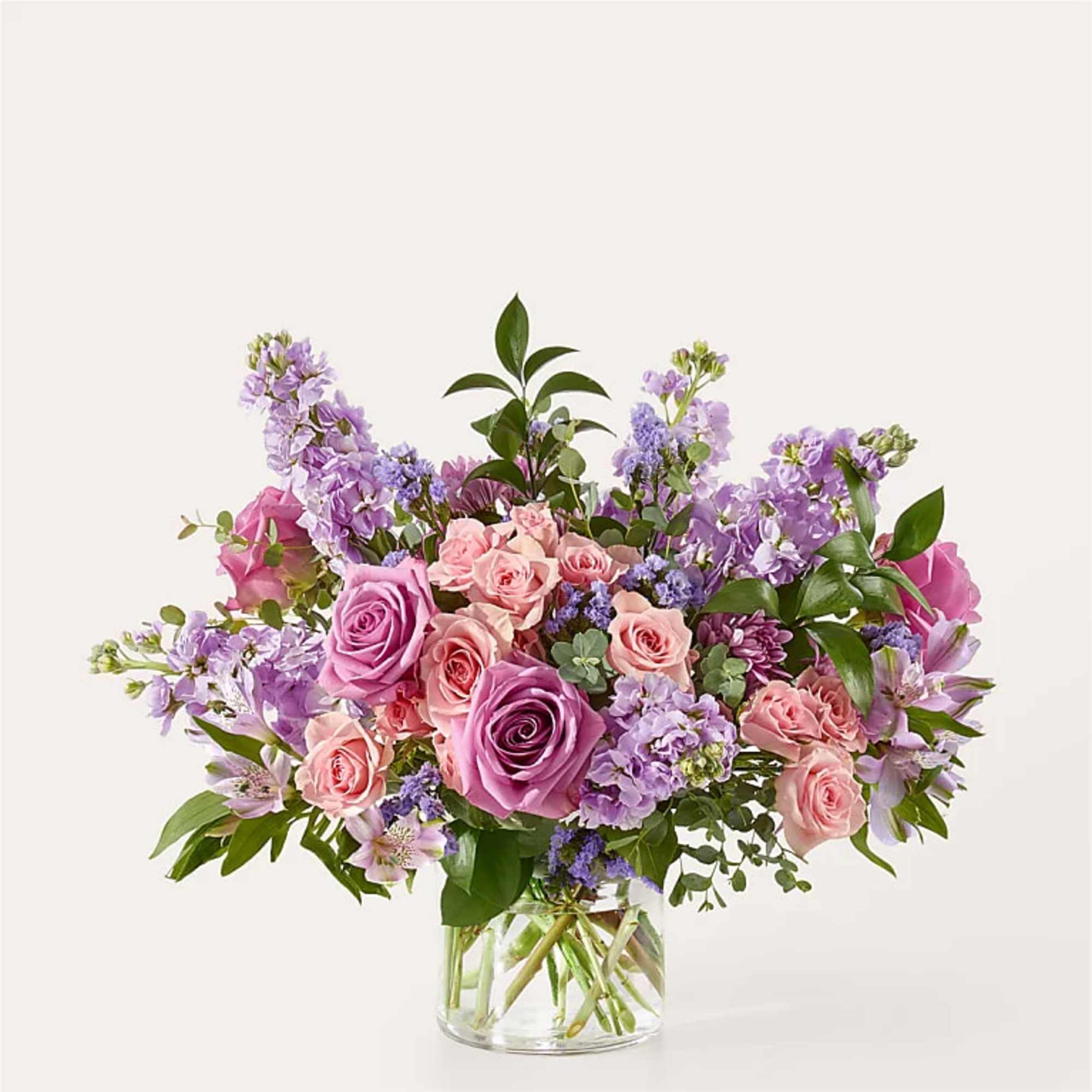 Pink and lavender roses arranged in a clear glass vase