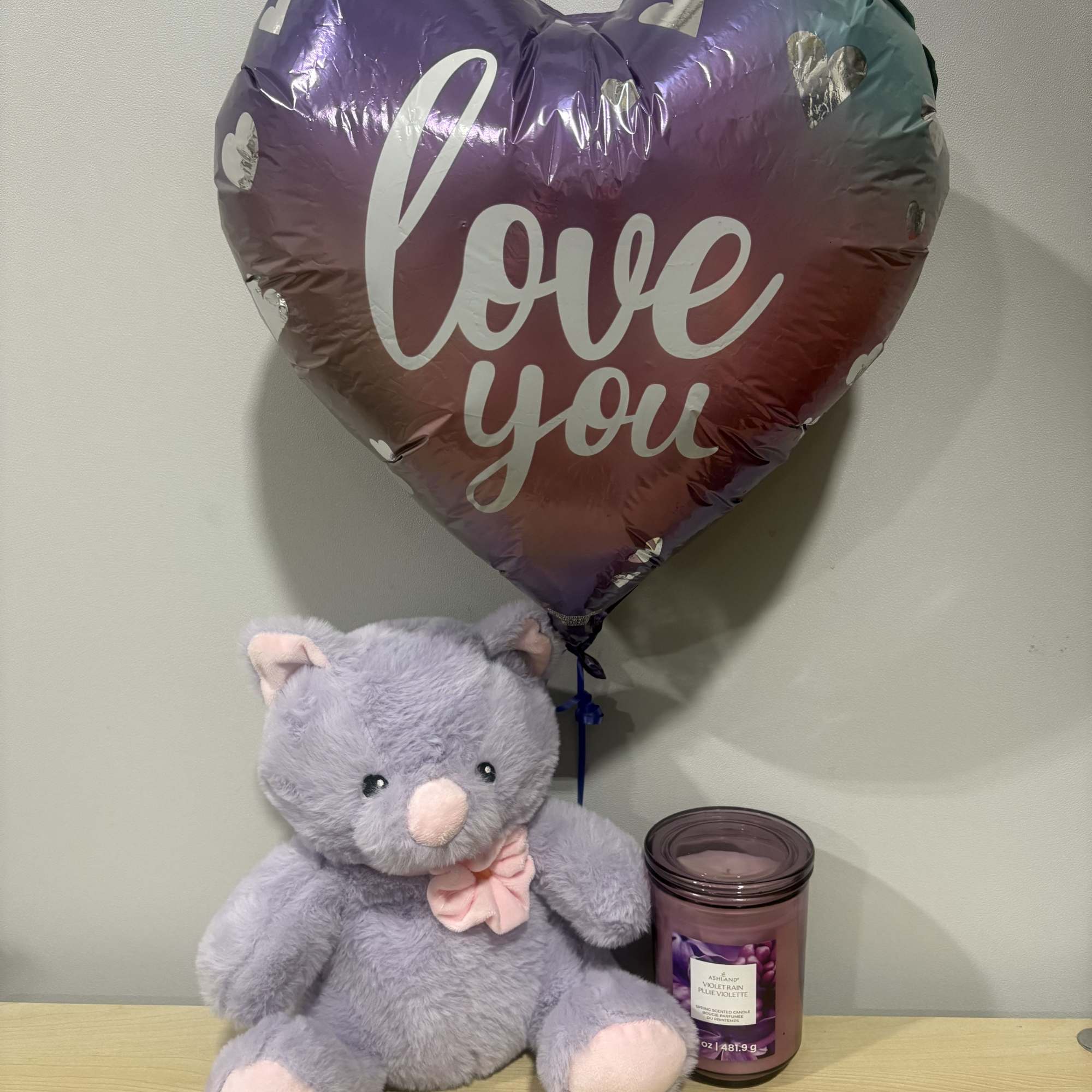 Heart-shaped "love you" balloon with a plush teddy bear and candle