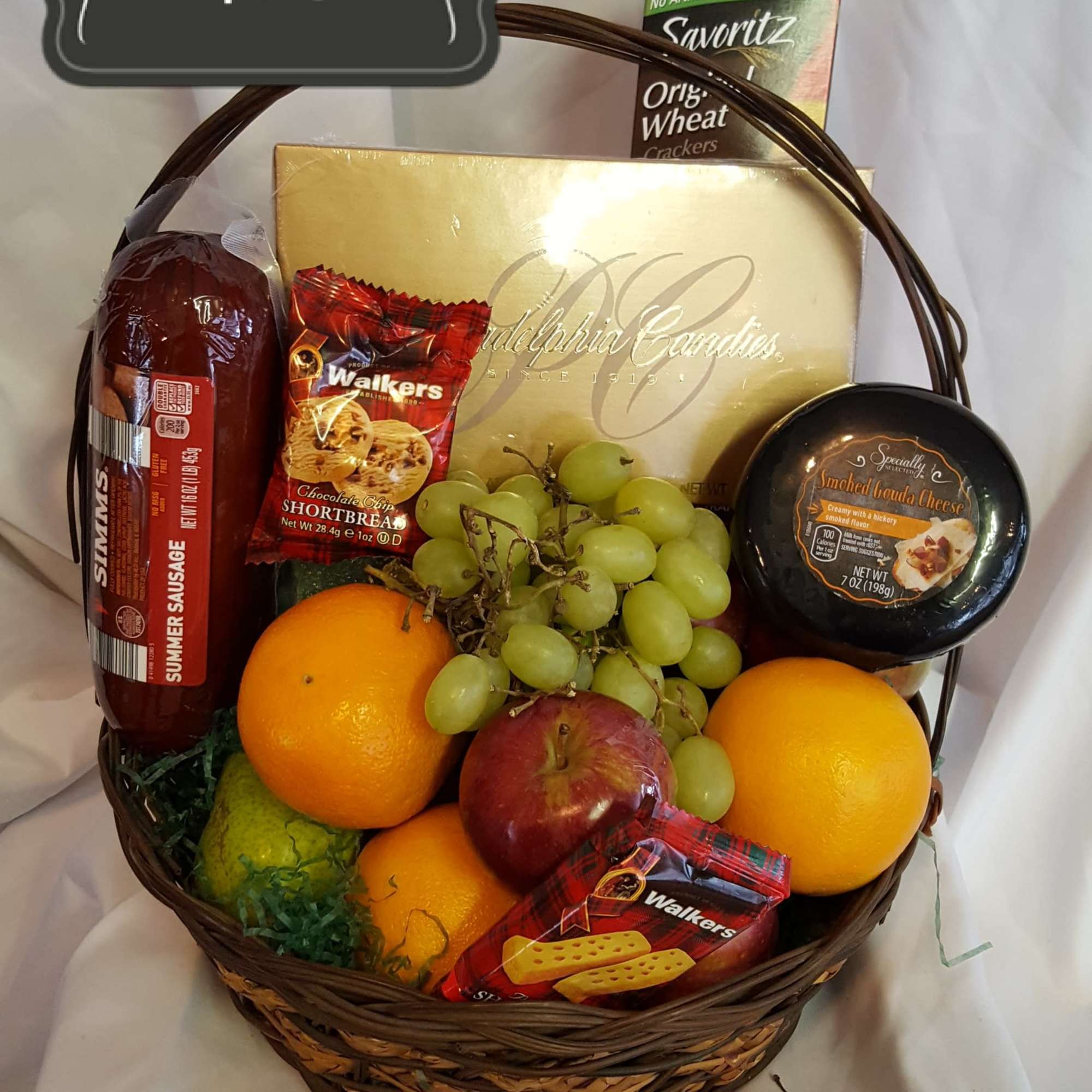 Gift basket with fruit, crackers, sausage, cheese, and snacks