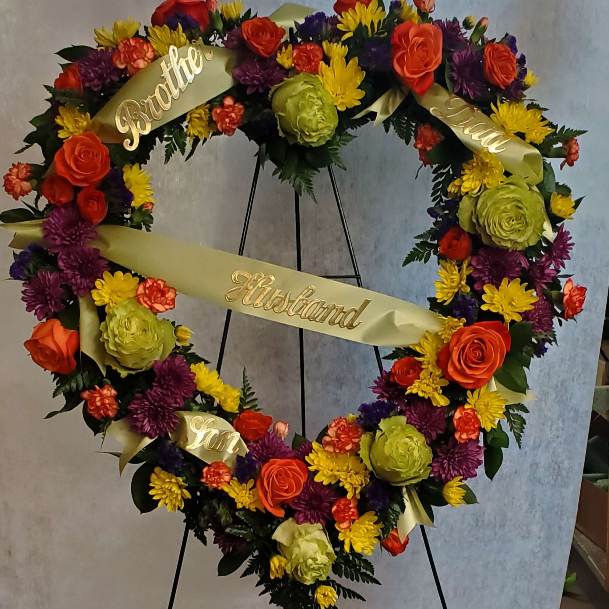 Heart-shaped floral wreath with ribbons and gold name lettering