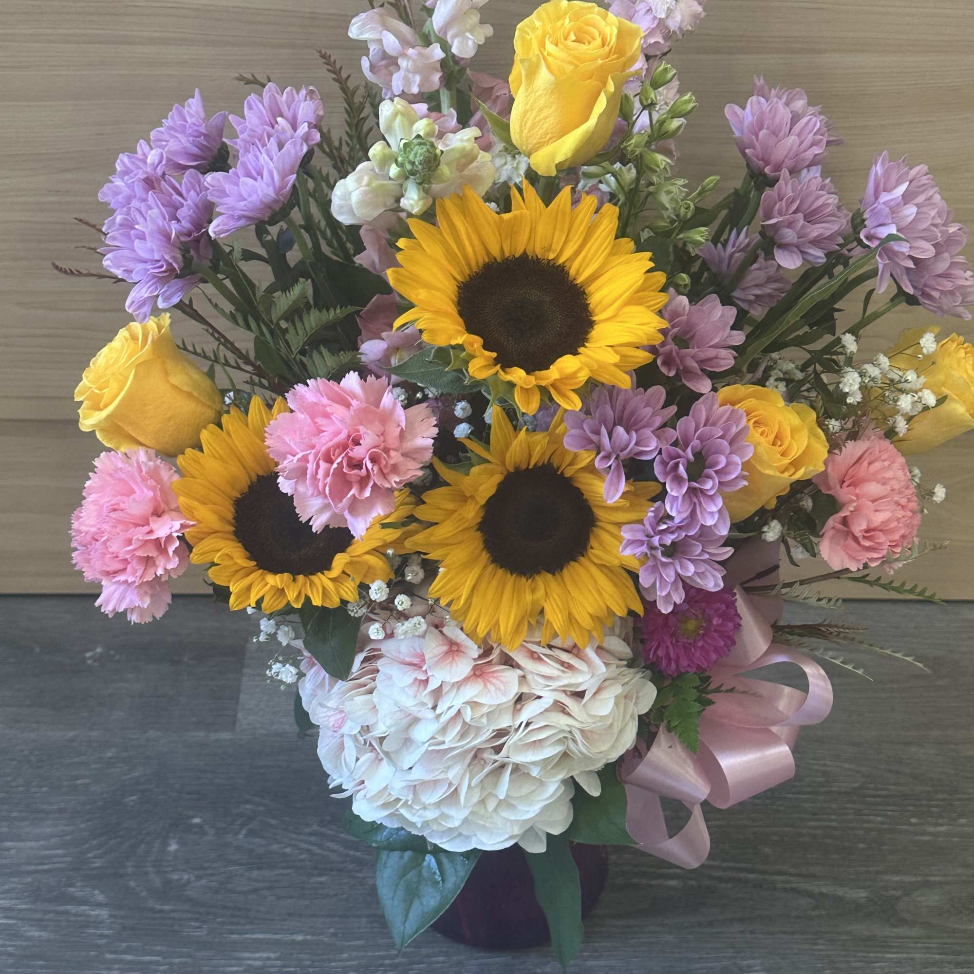 Mixed bouquet with sunflowers, yellow roses, pink carnations, and lavender blooms
