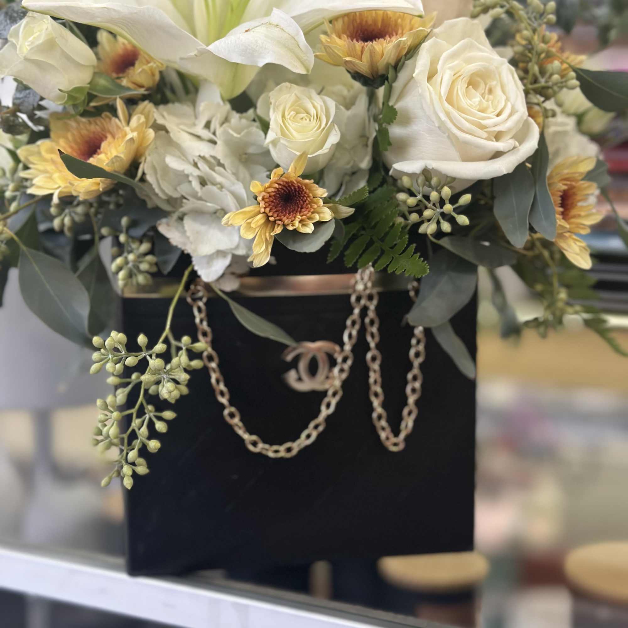 White lilies and roses in a black box with gold chain trim